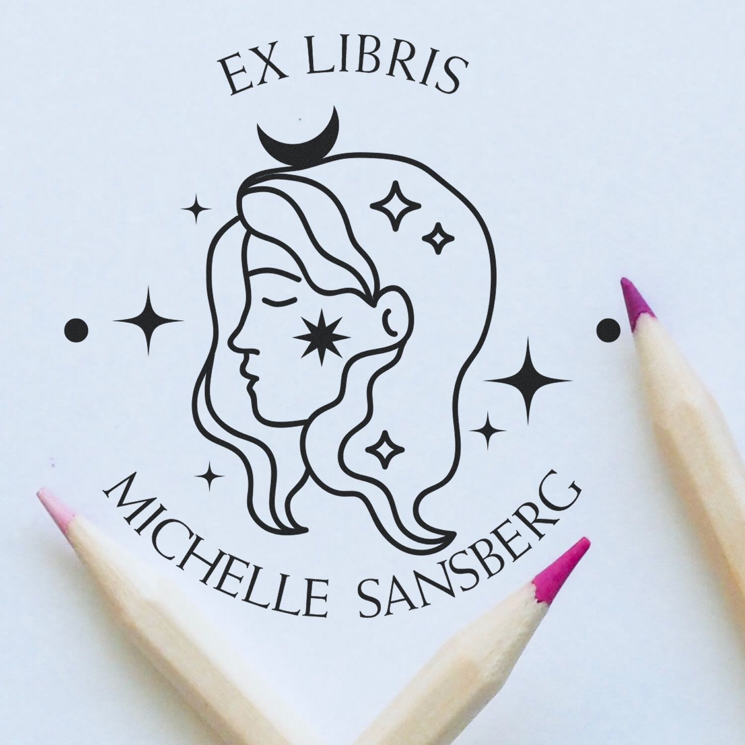 Black Ex Libris stamp seal with stylized woman face and stars on white paper, framed by pink-tipped pencils.
