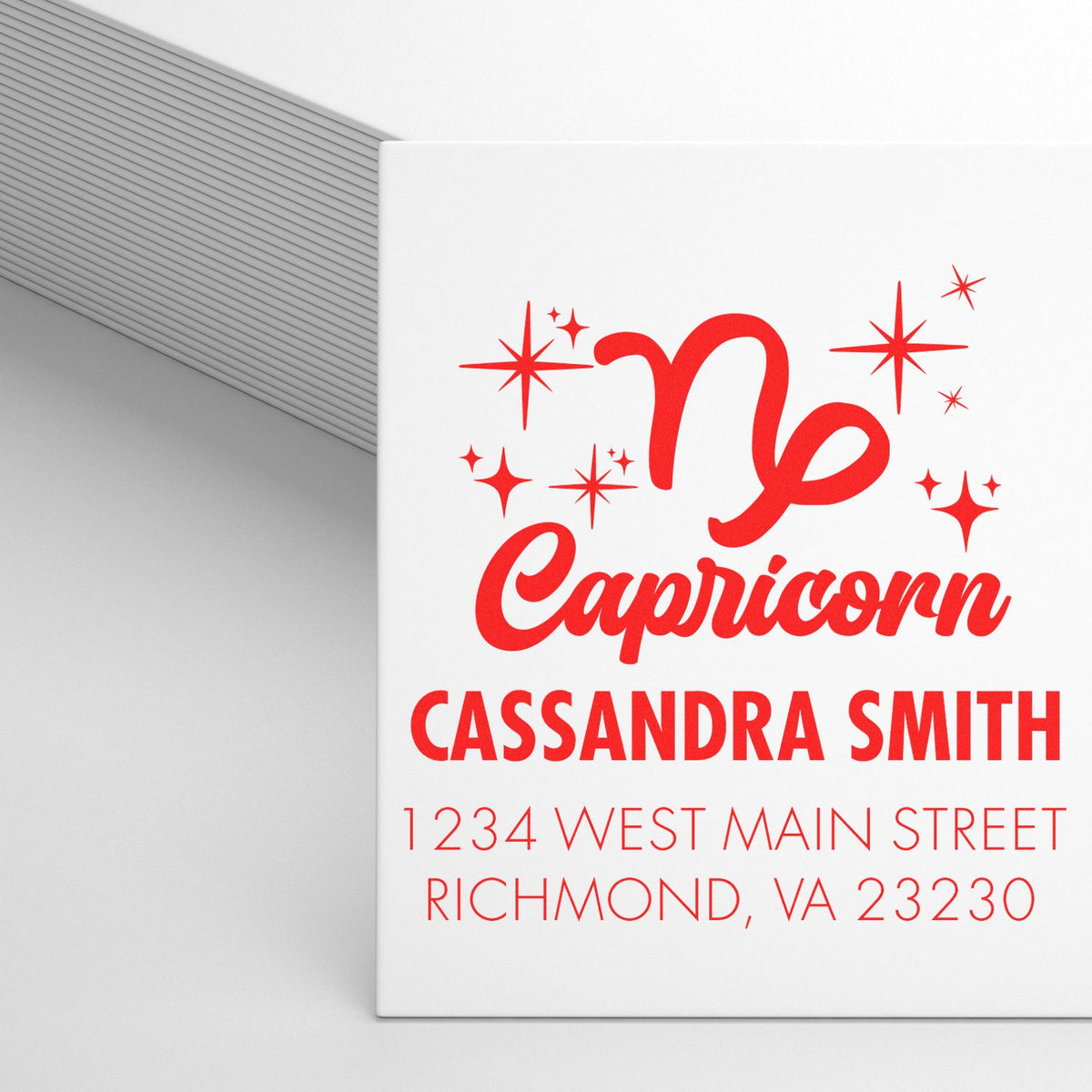 White stamp and seal product featuring red Capricorn design, Cassandra Smith name, address, and sparkle accents.