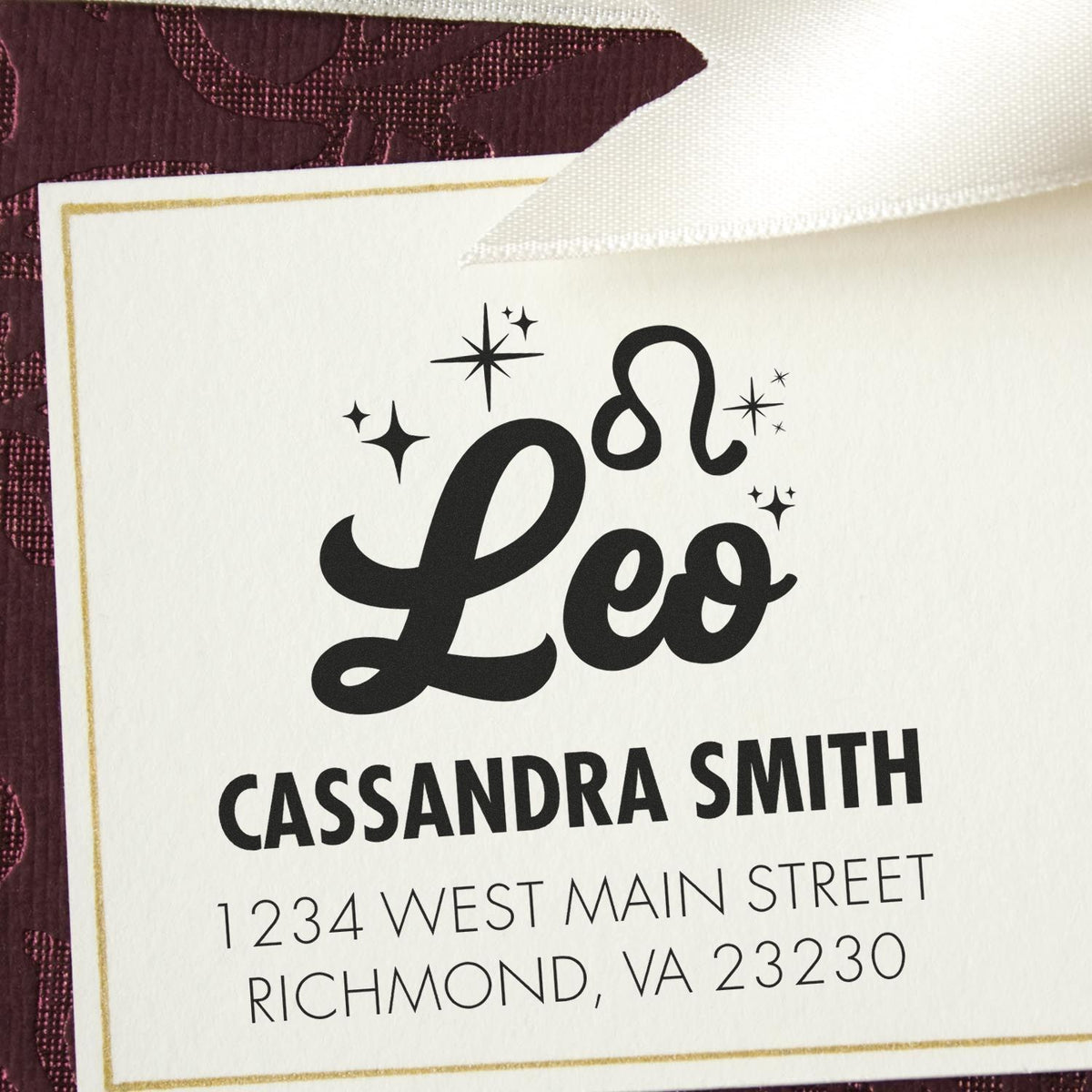 Personalized black Leo stamp and seal on white card with gold border, burgundy background, and sparkle accents.