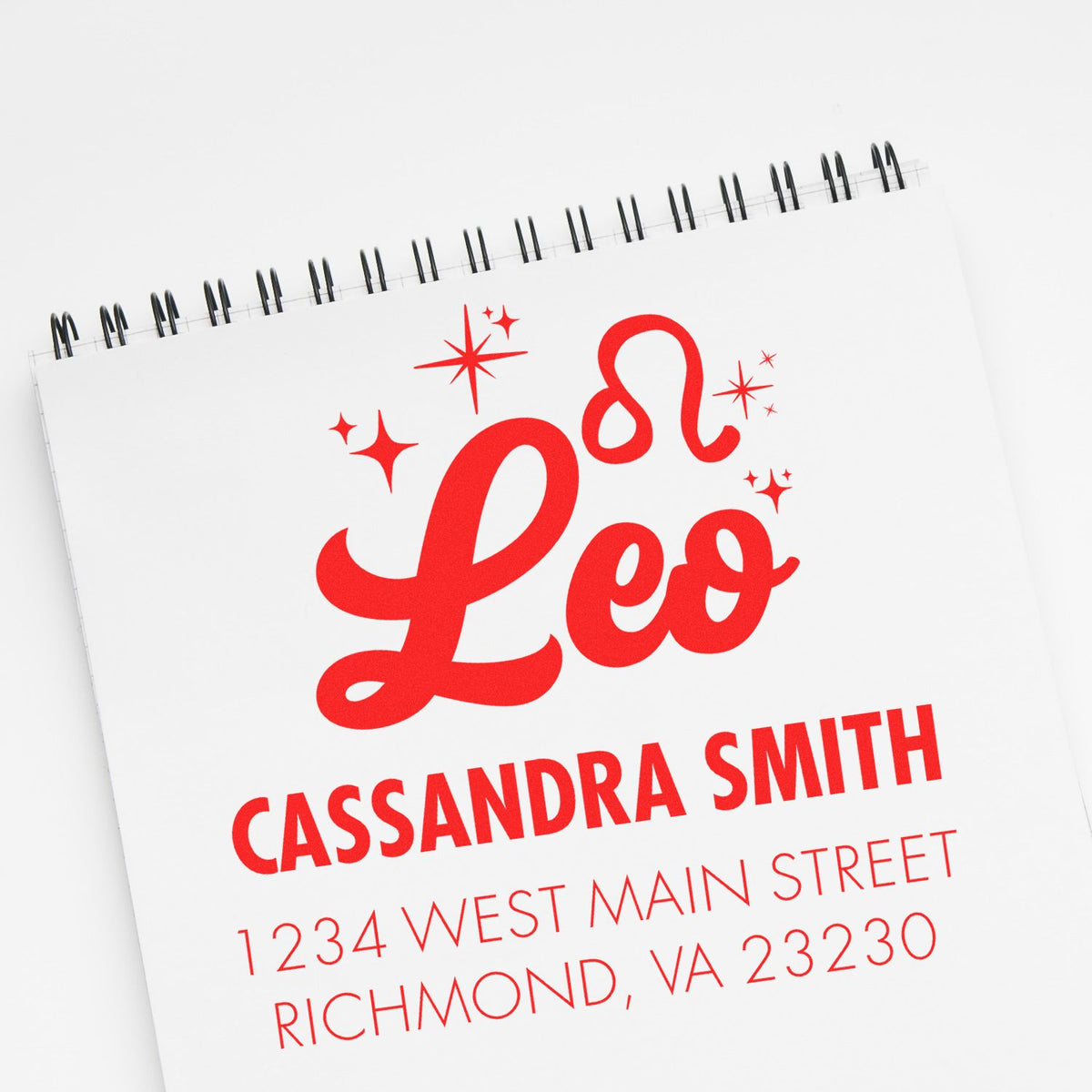 Red custom stamp and seal with Leo logo, Cassandra Smith name, and Richmond address on a white spiral notepad.