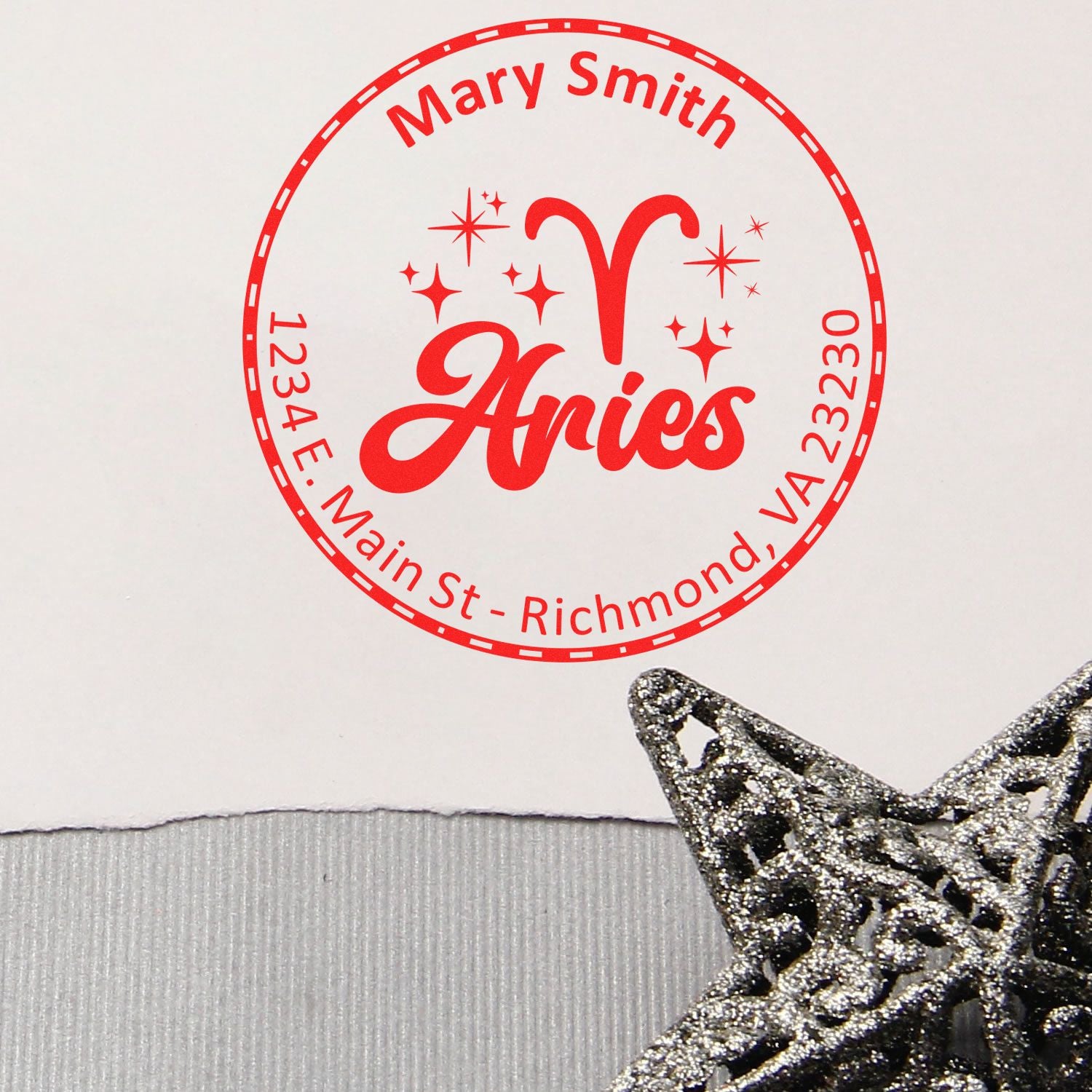 Red custom address stamp seal for Mary Smith, Aries, with circular border, sparkles, and silver star charm on white.