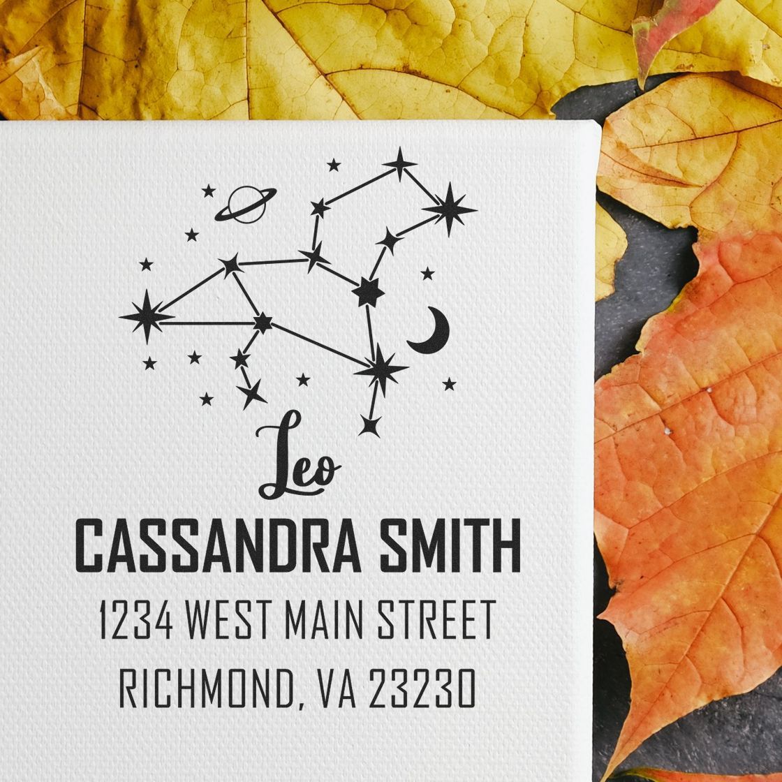 Personalized black Leo constellation stamp and seal with name and address on white card, surrounded by yellow-orange leaves.