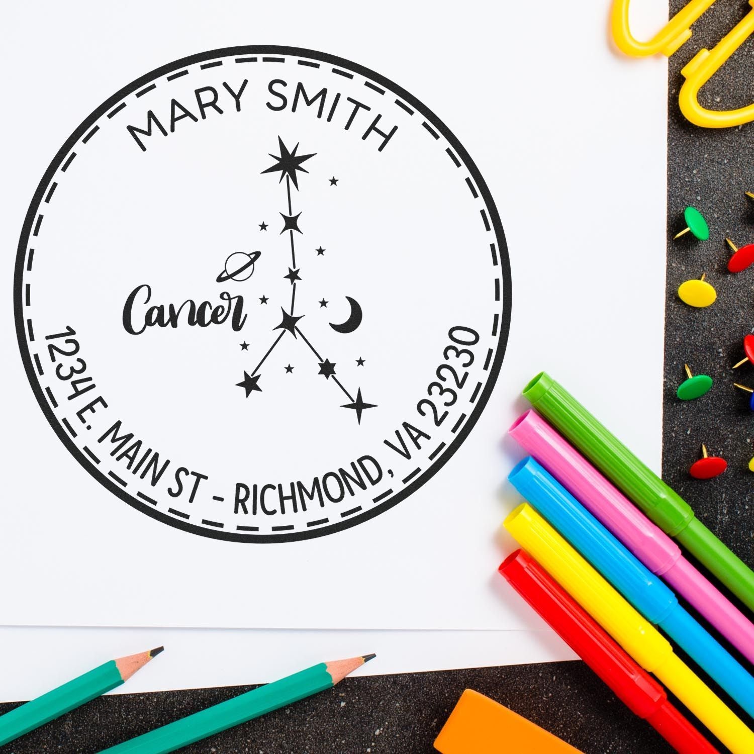 Black custom address stamp seal for Mary Smith with Cancer zodiac stars, surrounded by colorful markers and pencils