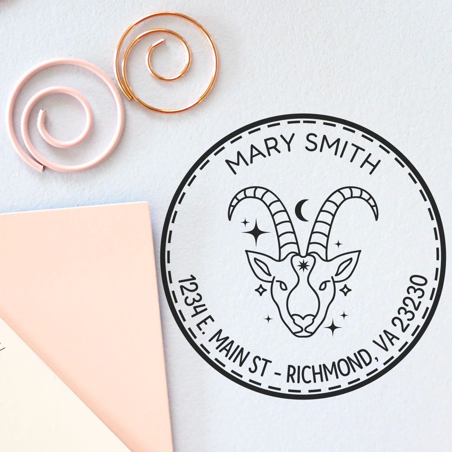 Custom black circular stamp seal with goat logo, Mary Smith, and address; pink and gold wax seal coils on white background.