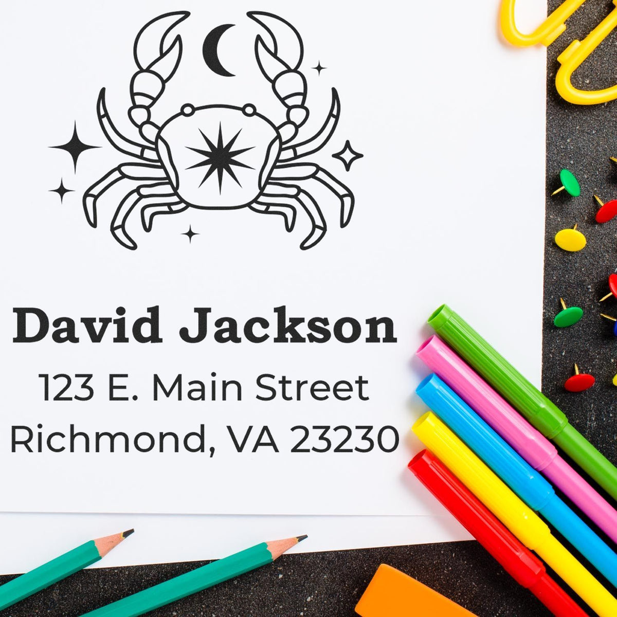 Black crab stamp seal with David Jackson, 123 E. Main Street, Richmond VA 23230, beside colorful pens and pencils