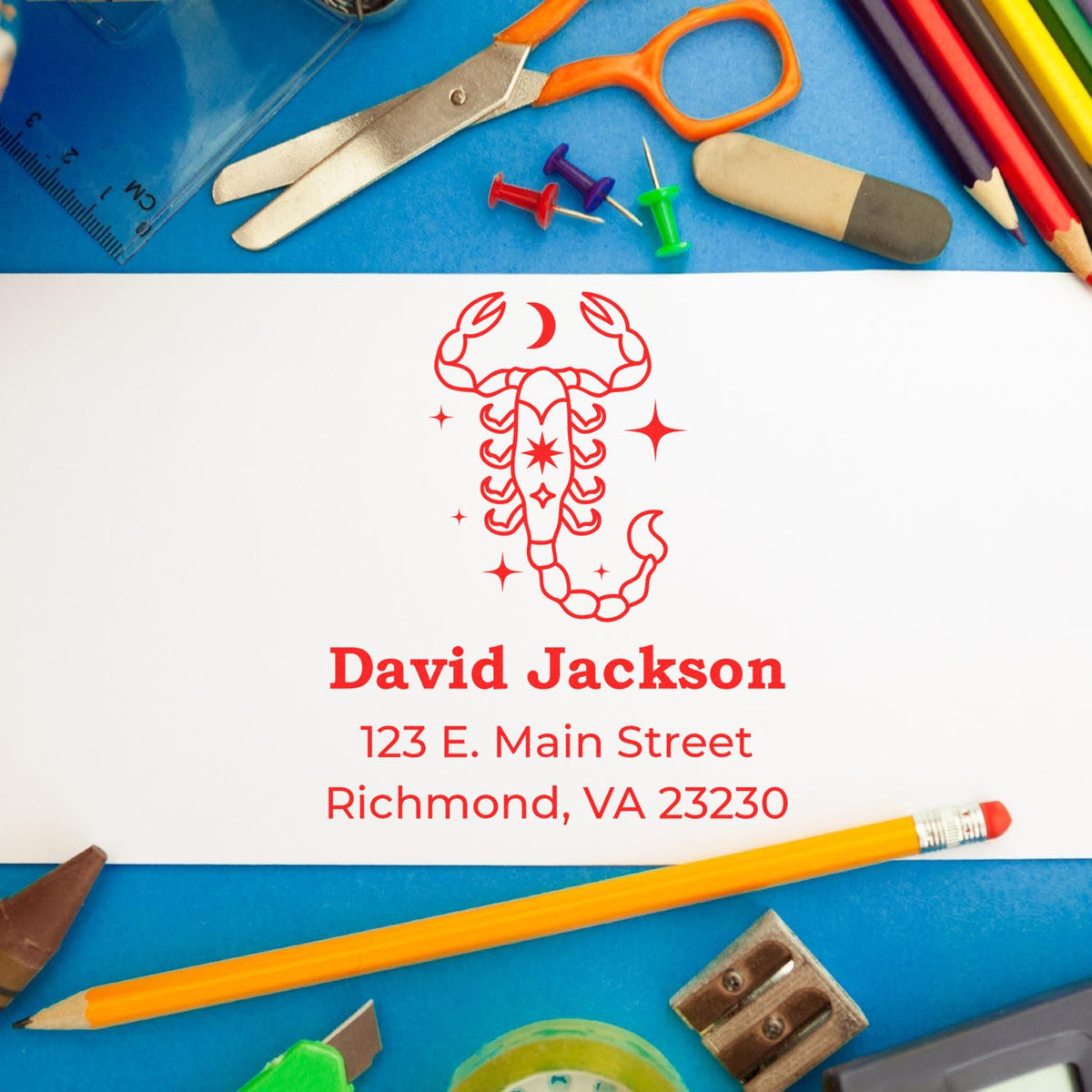 Red scorpion stamp seal with David Jackson name and Richmond, VA address on white card, surrounded by colorful school supplies.