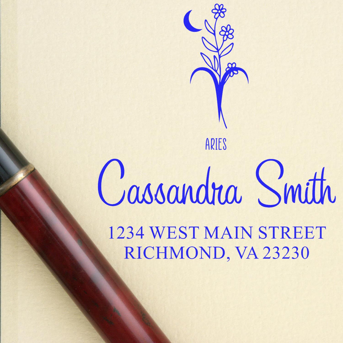 Blue personalized stamp and seal impression with Aries floral symbol, Cassandra Smith name and Richmond, VA address on beige paper.