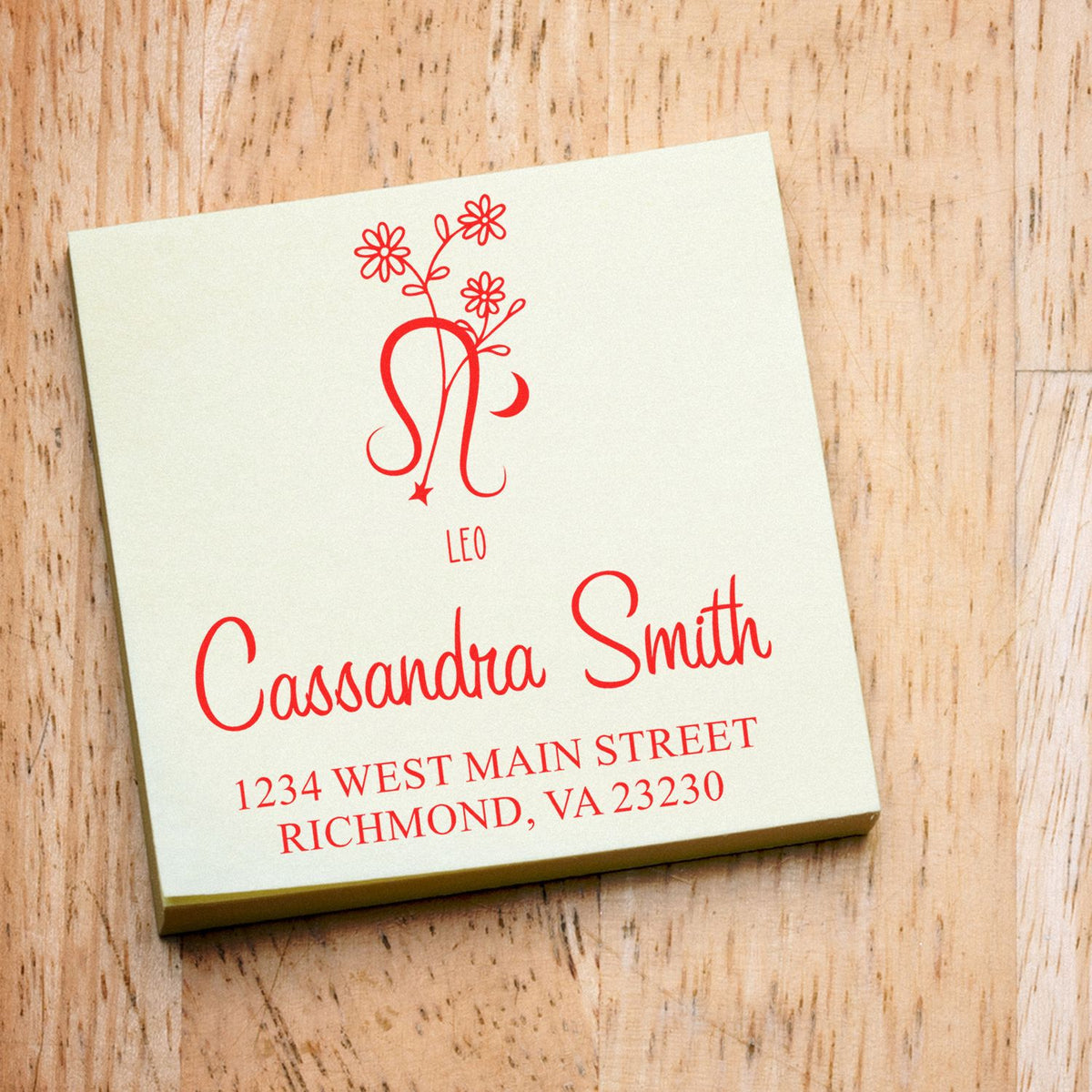 Cream custom stamp and seal with red Leo floral monogram, Cassandra Smith name, and address on wood.