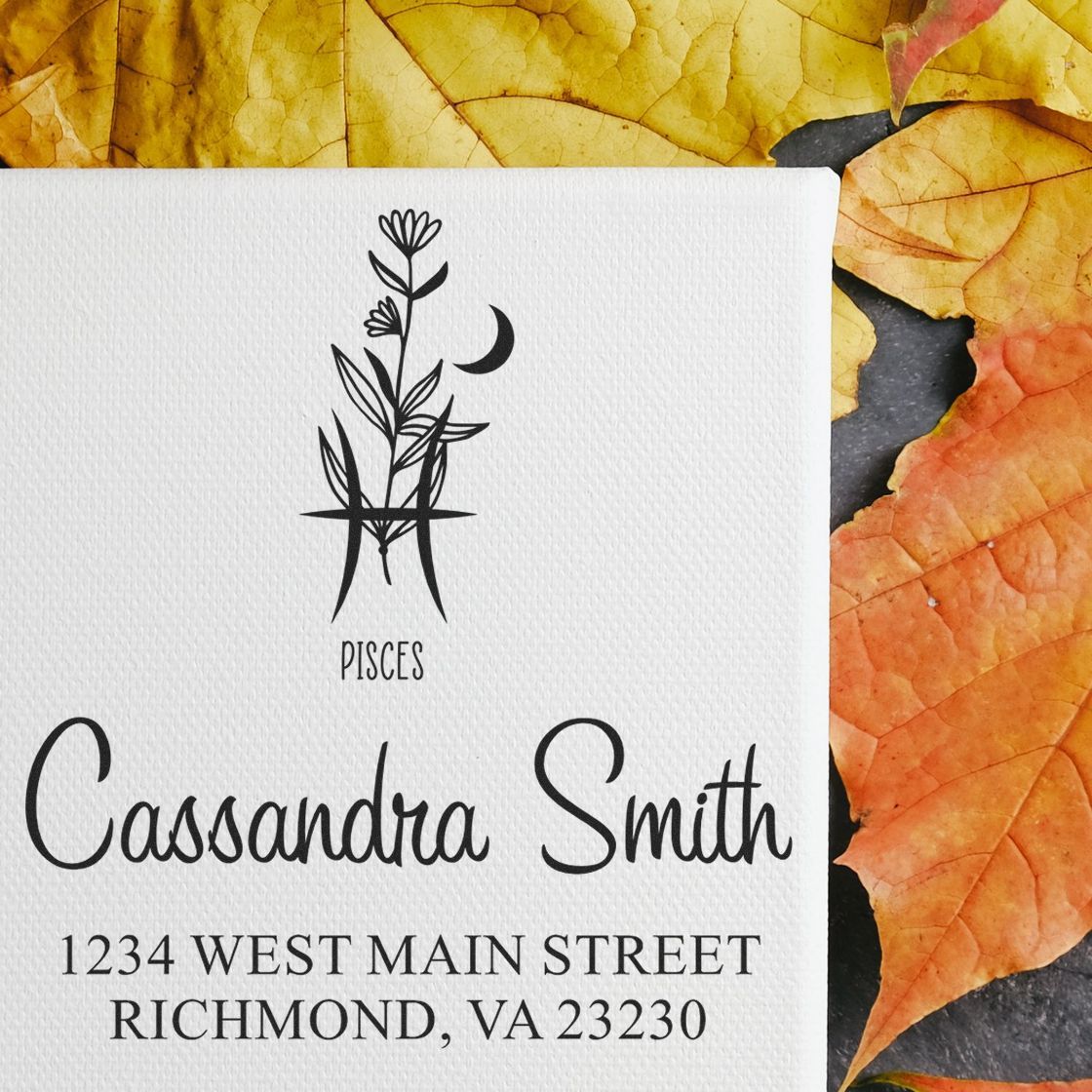 Custom black Pisces stamp seal with floral monogram, Cassandra Smith name, and Richmond address on white card, autumn leaves.