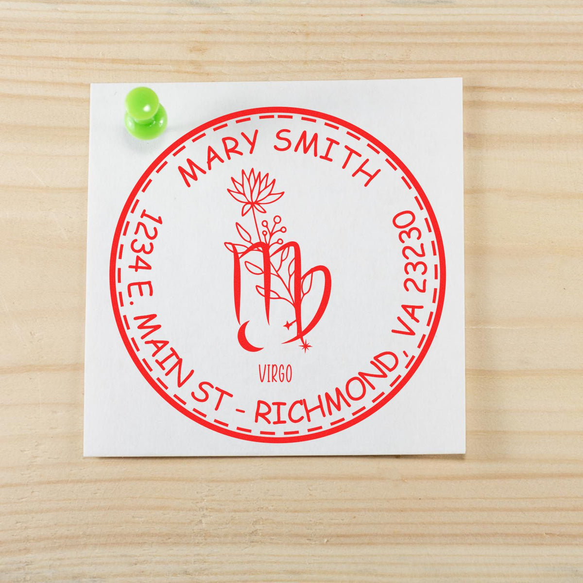 Custom red circular address stamp seal for Mary Smith, Virgo, on white card with green tack over light wood.