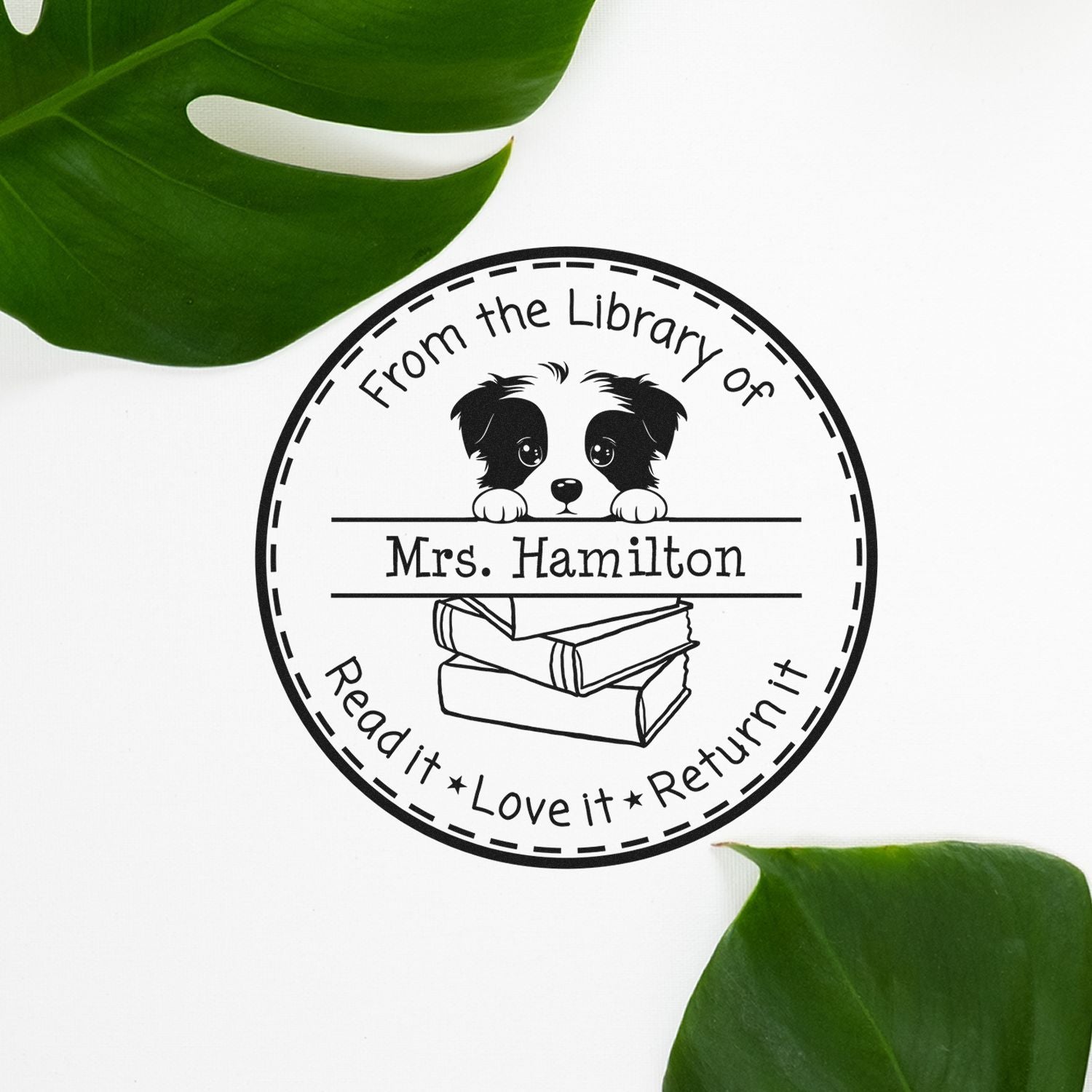 Black circular library stamp seal with puppy and books, From the Library of Mrs. Hamilton, on white with green leaves.