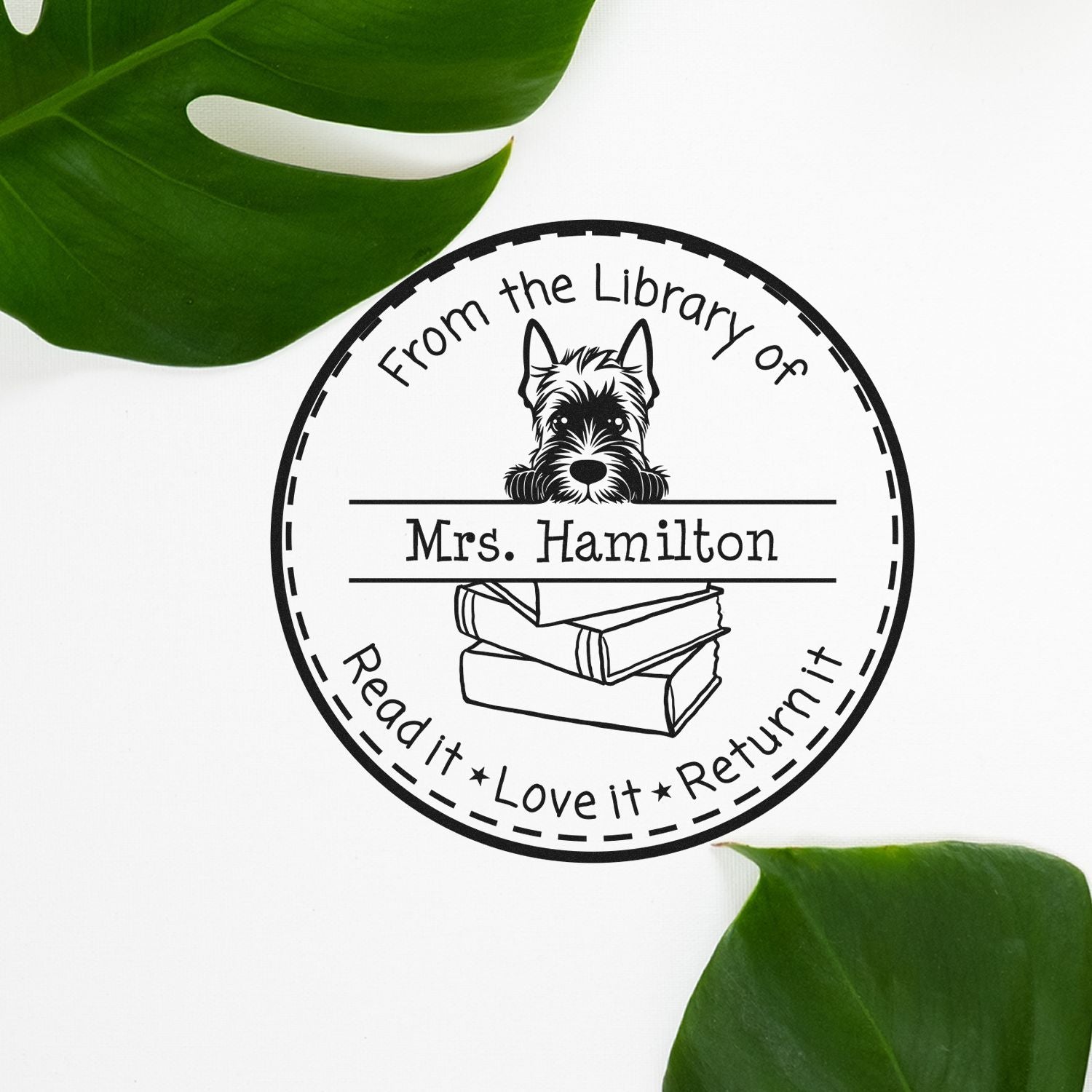 Round black custom library book stamp seal with dog, books, and Mrs. Hamilton; green leaves on white.