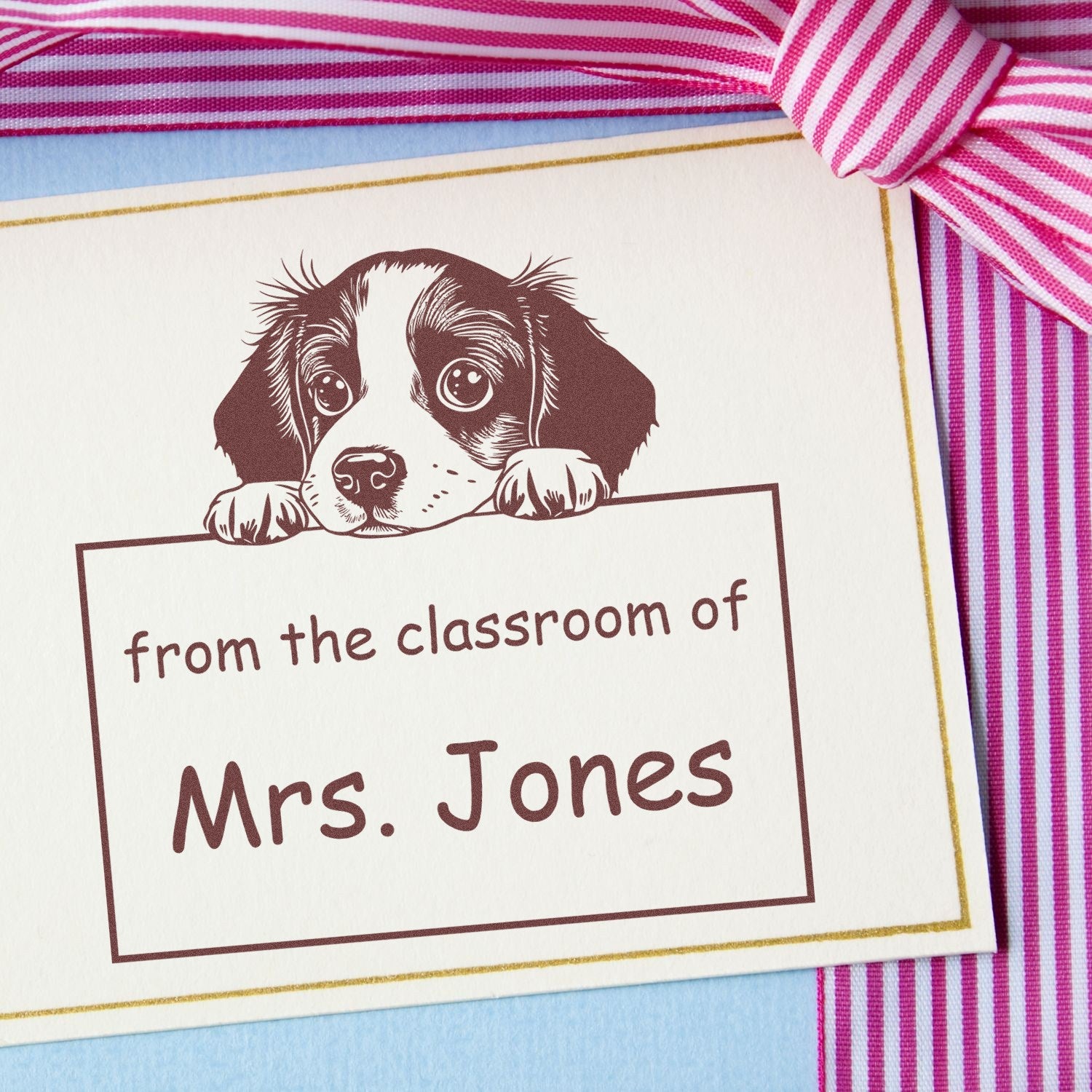 Personalized classroom stamp seal with puppy illustration, Mrs. Jones text, and pink striped ribbon on cream card