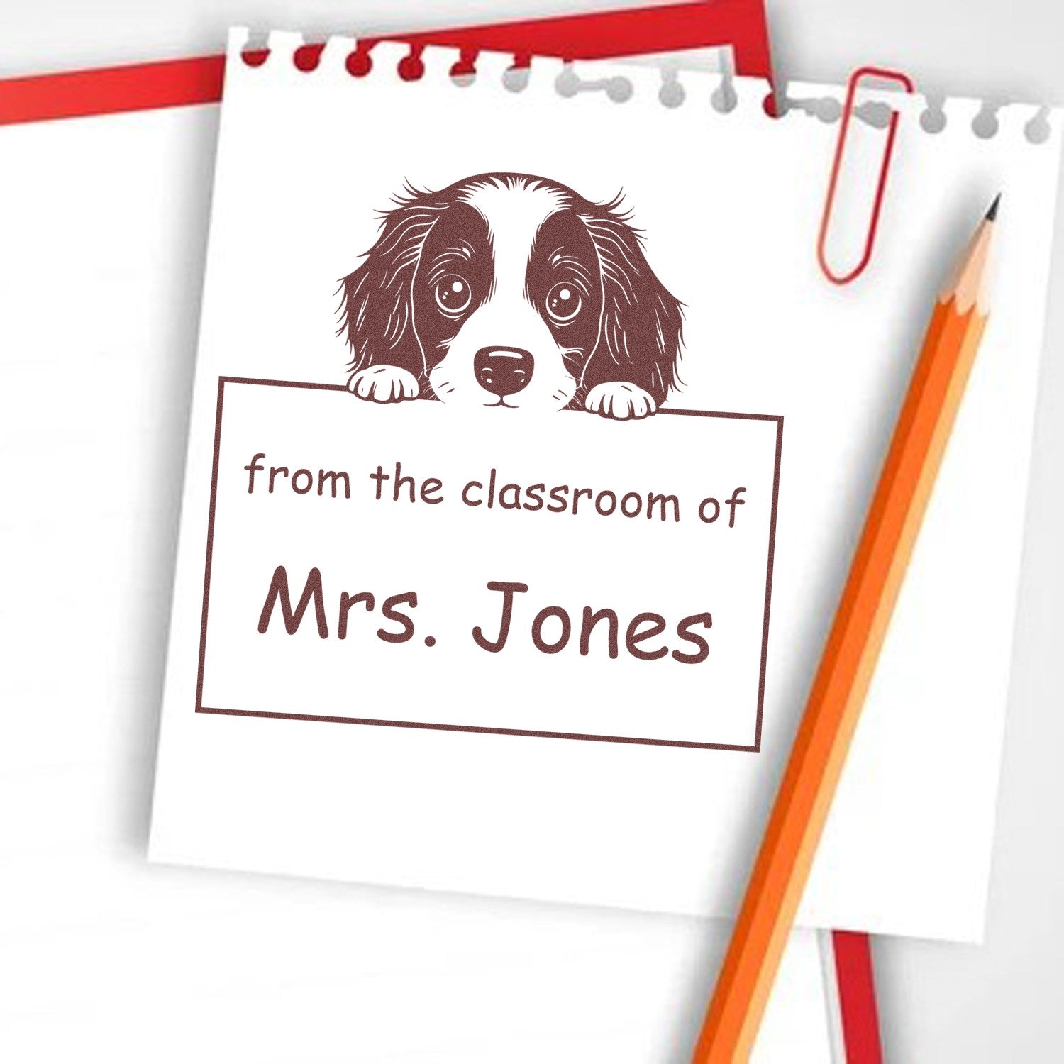 Brown puppy classroom stamp/seal reading from the classroom of Mrs. Jones on white paper, with red paperclip and pencil.