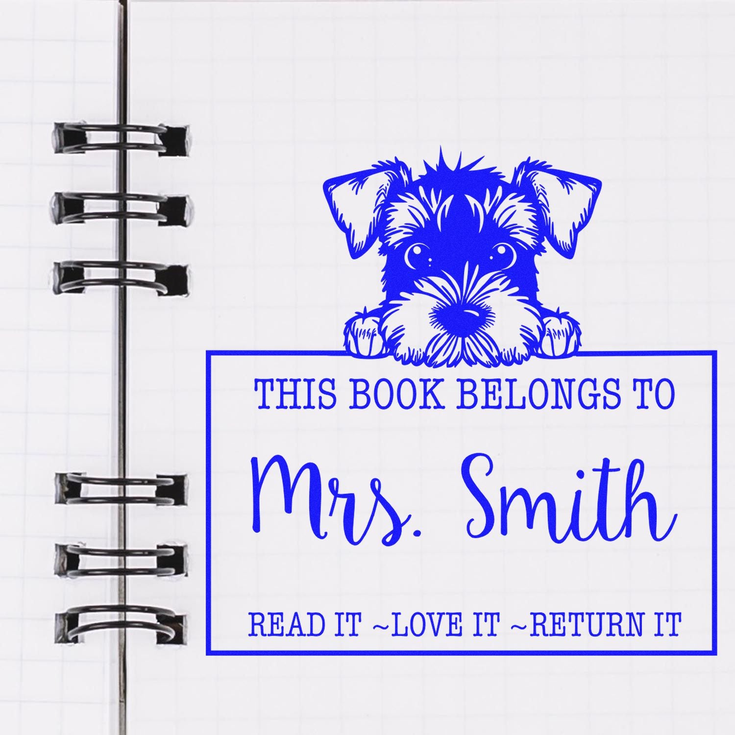 Blue custom book stamp and seal with a dog, reading This book belongs to Mrs. Smith, on a white notebook page.