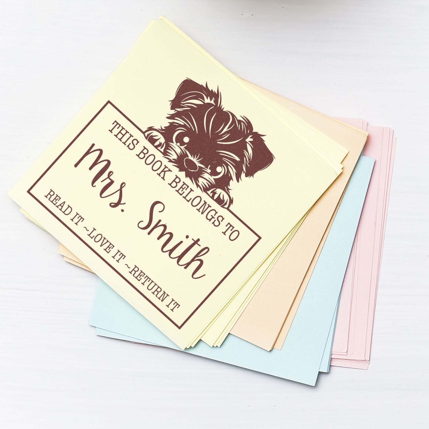 Pastel book stamp seals with brown puppy design and This Book Belongs to Mrs. Smith on stacked cards.