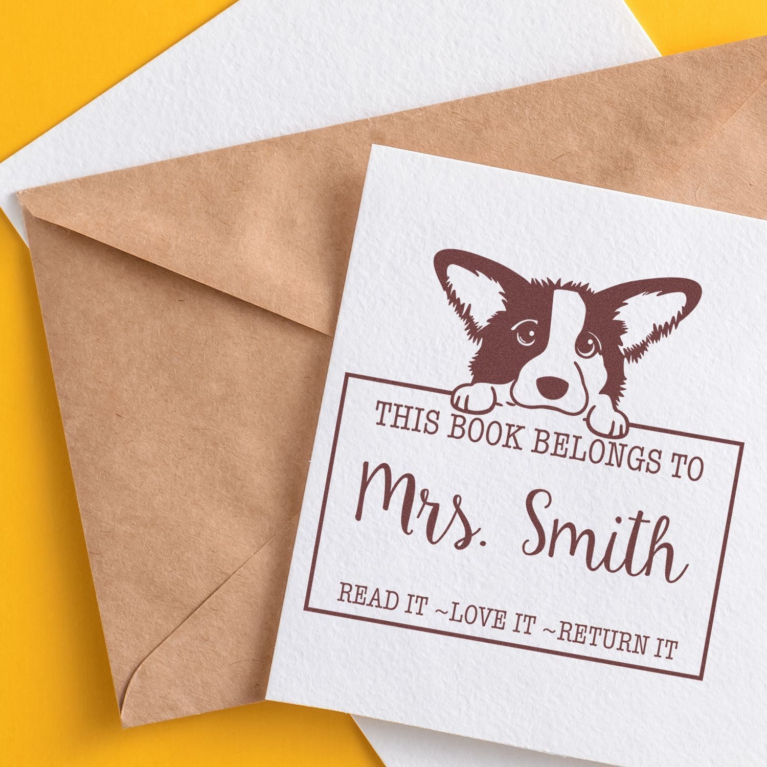 Brown custom book stamp seal with corgi and This book belongs to Mrs. Smith on a white card over yellow background.
