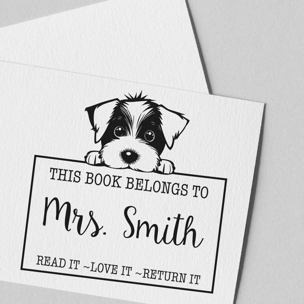 Black-and-white custom book stamp with puppy seal and text, This book belongs to Mrs. Smith, on textured white paper.