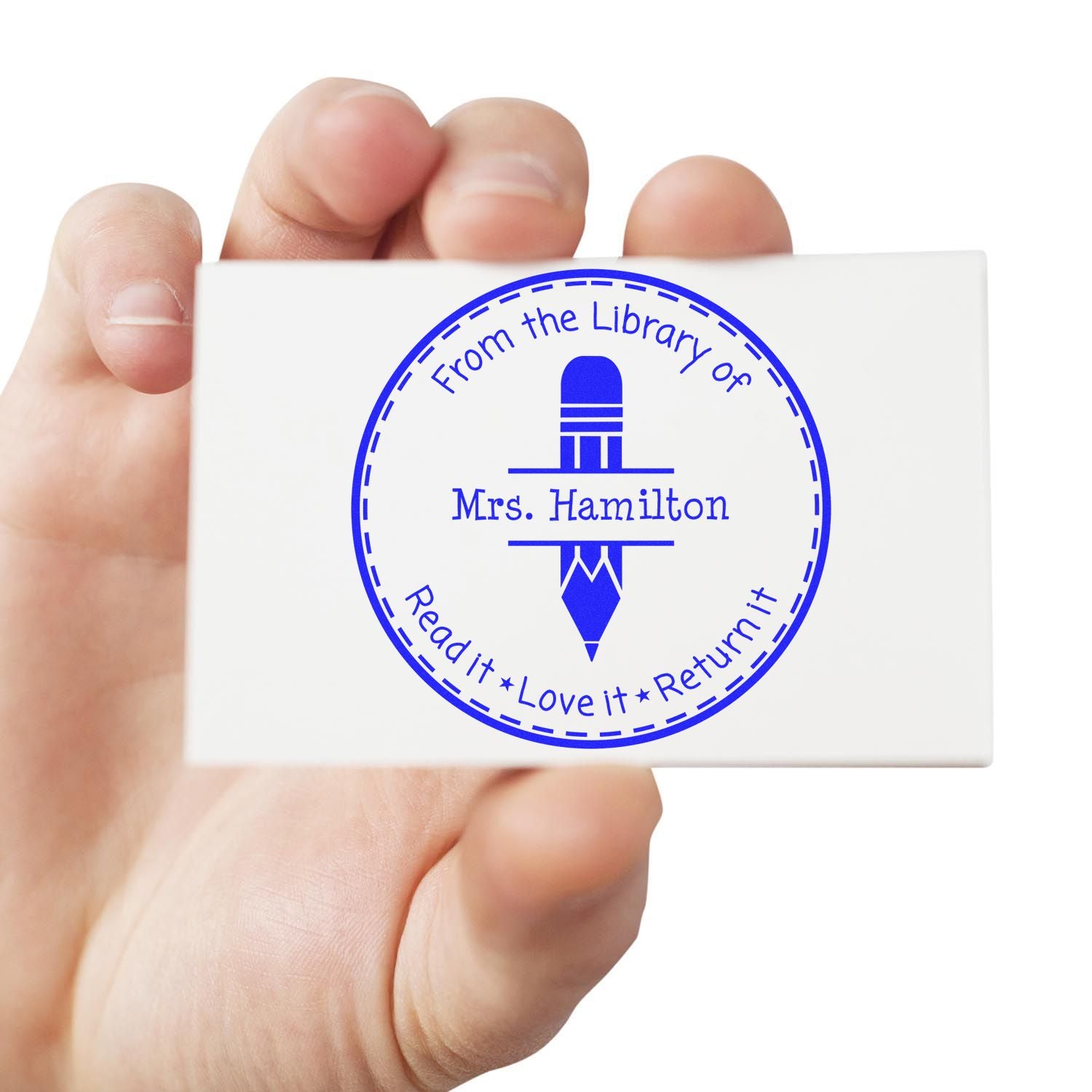 Handheld white library stamp with blue circular seal, pencil icon, and From the Library of Mrs. Hamilton text