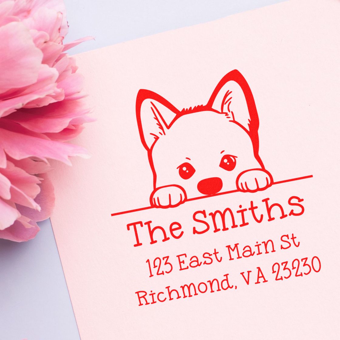 Red custom address stamp seal with fox peeking over line on pink paper, beside pink flowers.