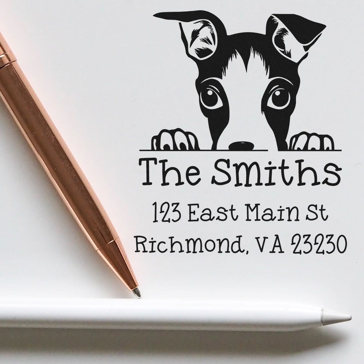 Black custom stamp and seal with playful dog graphic, The Smiths address, on white paper with rose-gold pen and white stylus.