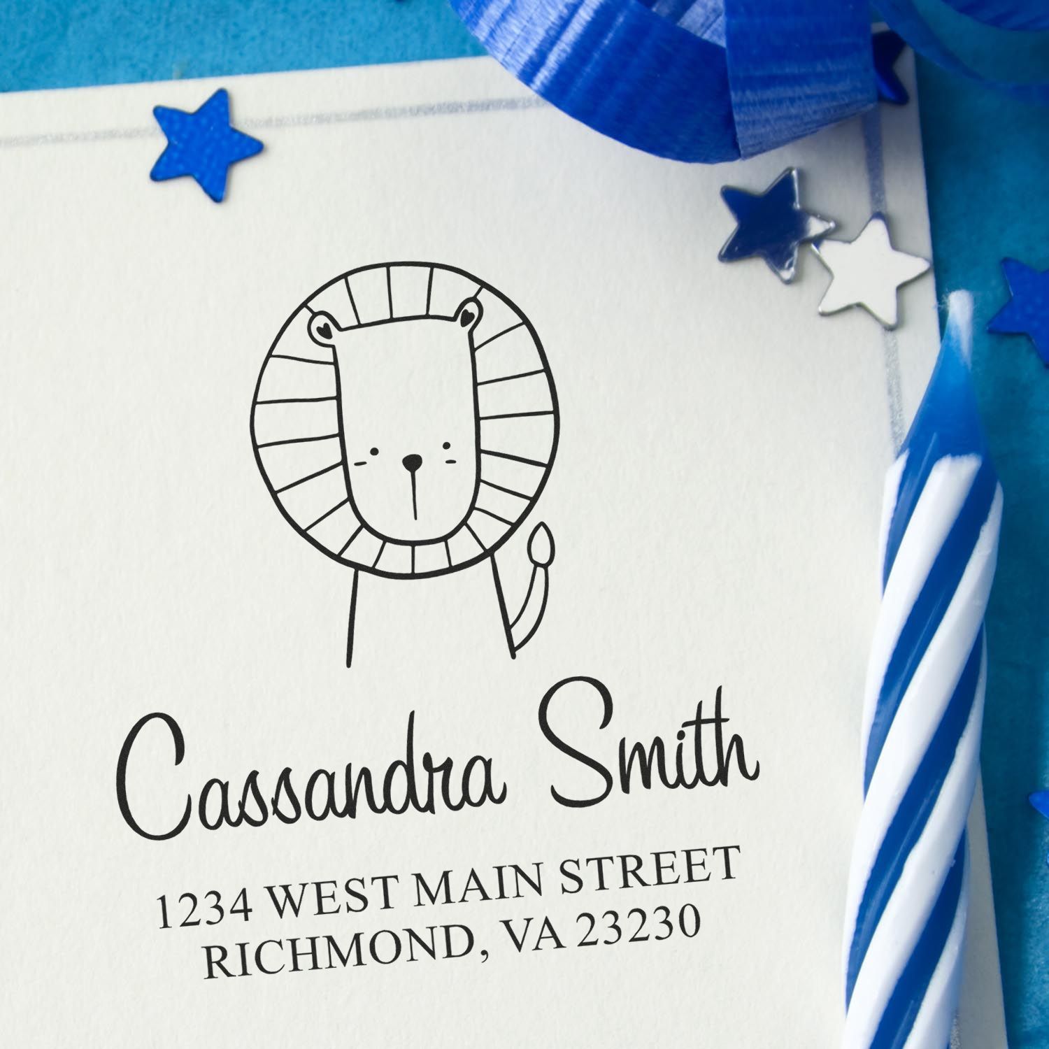 Self-Inking Cartoon Animal Little Roar Custom Made Return Address Stamp featuring a cute lion design on an envelope. The Customized Address Stamp displays "Cassandra Smith, 1234 West Main Street, Richmond, VA 23230" with blue decorations and a striped candle nearby.