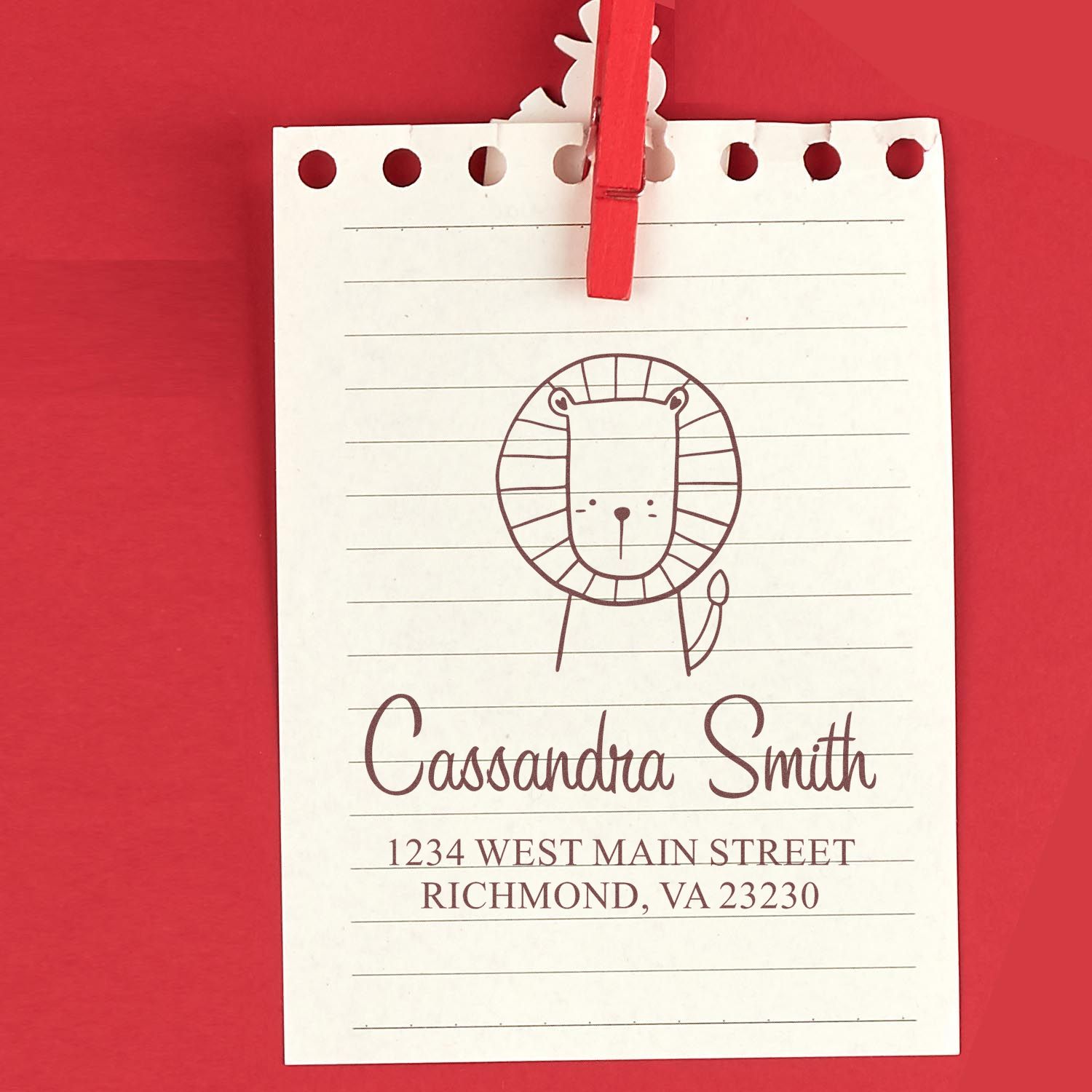 Wood handle Little Roar cartoon animal made to order return address stamper on red paper. Personalized mailing stamp with a cute lion design, featuring the name "Cassandra Smith" and address "1234 West Main Street, Richmond, VA 23230."