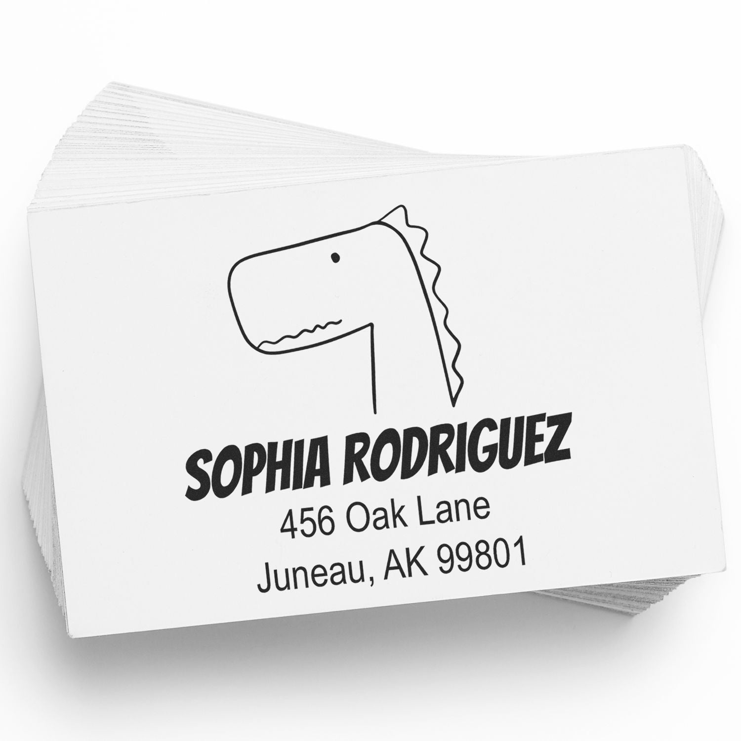 Self-Inking Cartoon Animal Mirthful Dino Custom Made Return Address Stamper in use, featuring a playful dinosaur illustration. The Custom-Made Home Stamp displays the name "Sophia Rodriguez" with an address in Juneau, AK on a stack of cards.