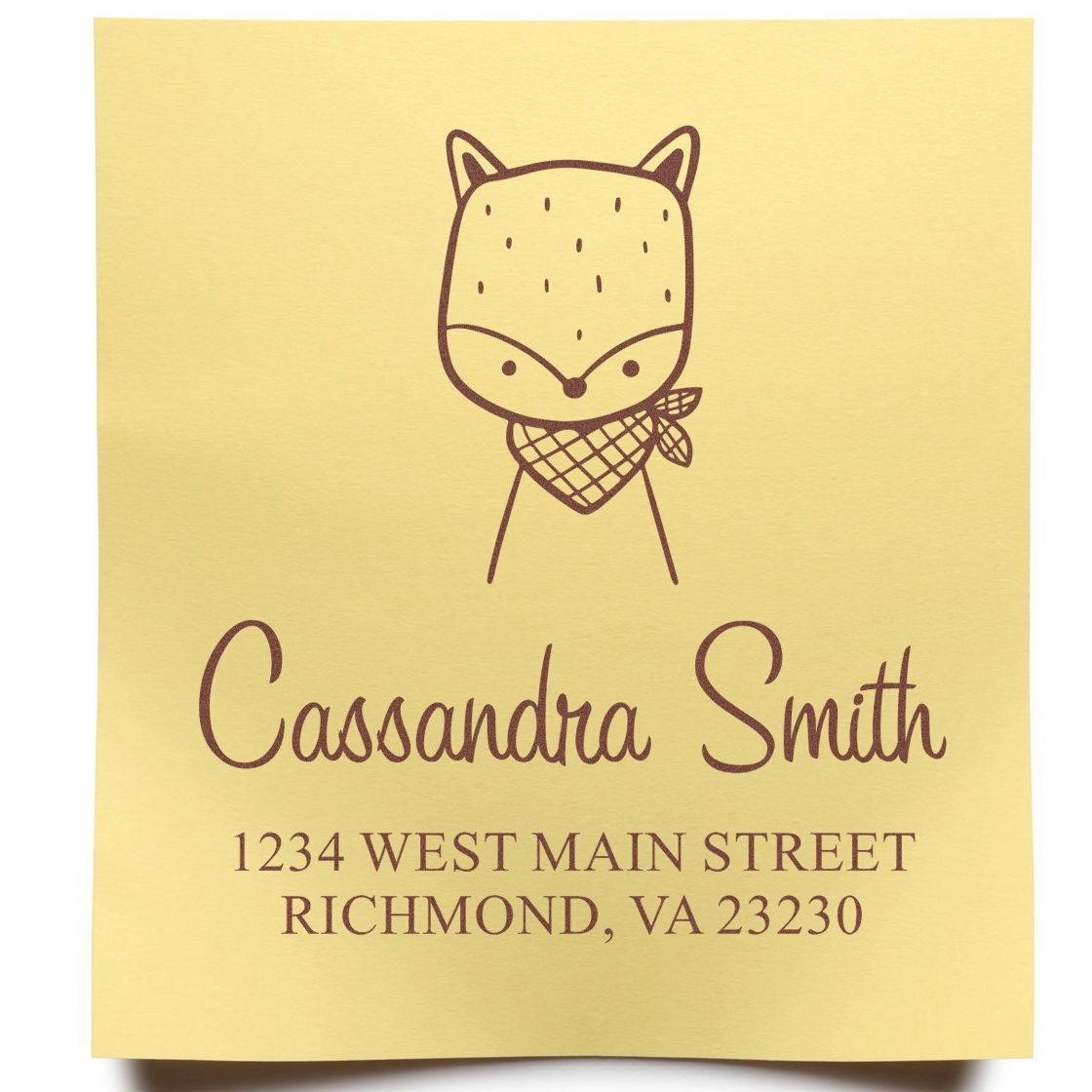 Self-inking cartoon animal fancy fox custom made name and address stamper on yellow paper. The design features a cute fox with a scarf, personalized with "Cassandra Smith, 1234 West Main Street, Richmond, VA 23230." Ideal for a customized mailing stamp.