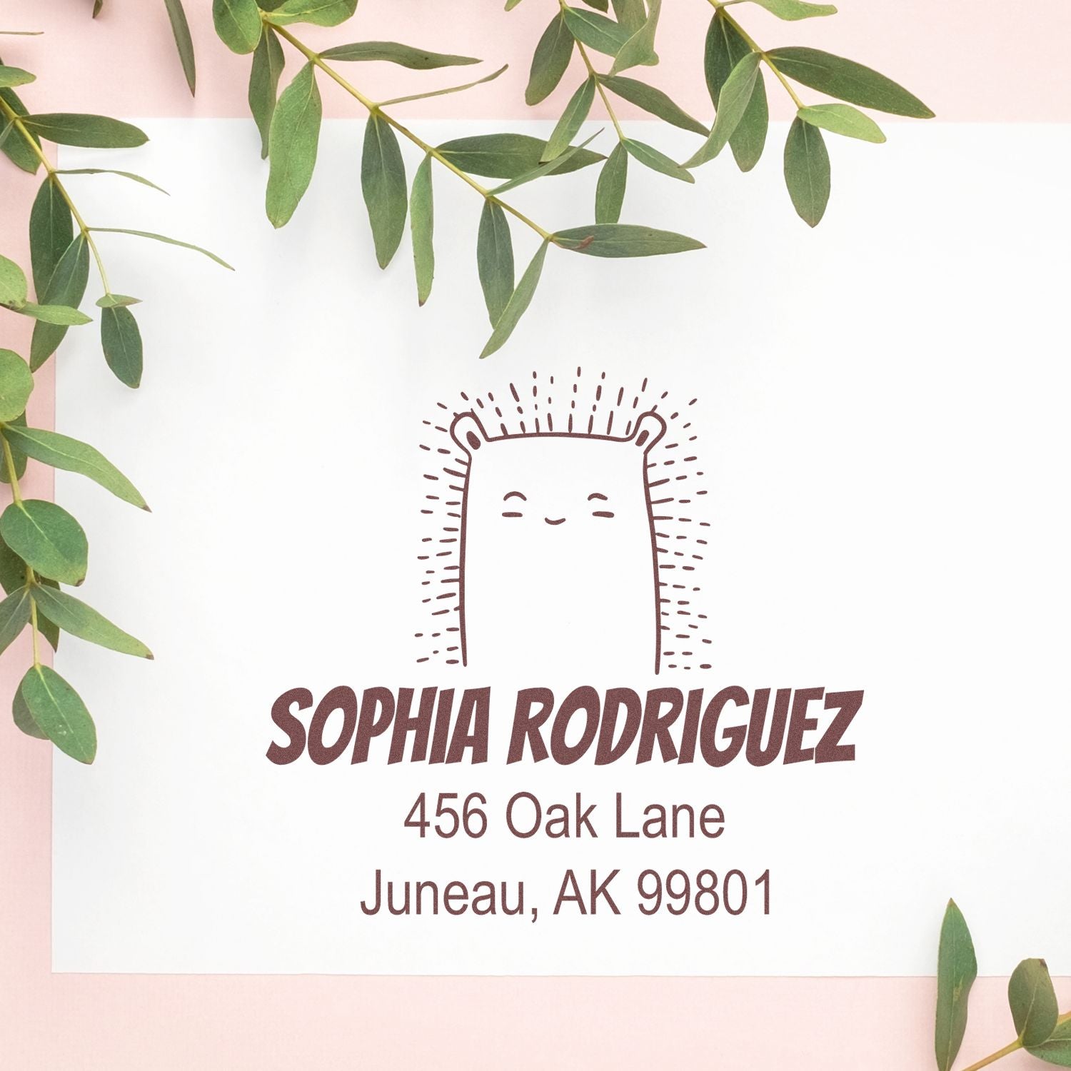 Wood Handle Bouncy Bear Cartoon Animal Custom Address Stamp on white paper with "Sophia Rodriguez, 456 Oak Lane, Juneau, AK 99801" text. Surrounded by green leaves, showcasing a personalizable home stamp design.