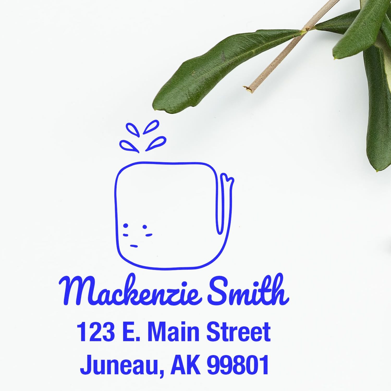 Self-Inking Cartoon Animal Joyful Whale Personalized Address Stamper with a playful whale design. Text reads "Mackenzie Smith, 123 E. Main Street, Juneau, AK 99801." Personalizable Home Stamp next to green leaves on a white background.