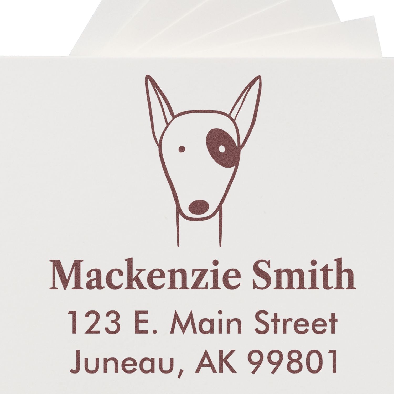 Self-Inking Cartoon Animal Delightful Dog Personalized Home Stamp featuring a simple dog illustration with one eye patch. The stamp displays the name "Mackenzie Smith" and address "123 E. Main Street, Juneau, AK 99801" in brown ink on white paper.