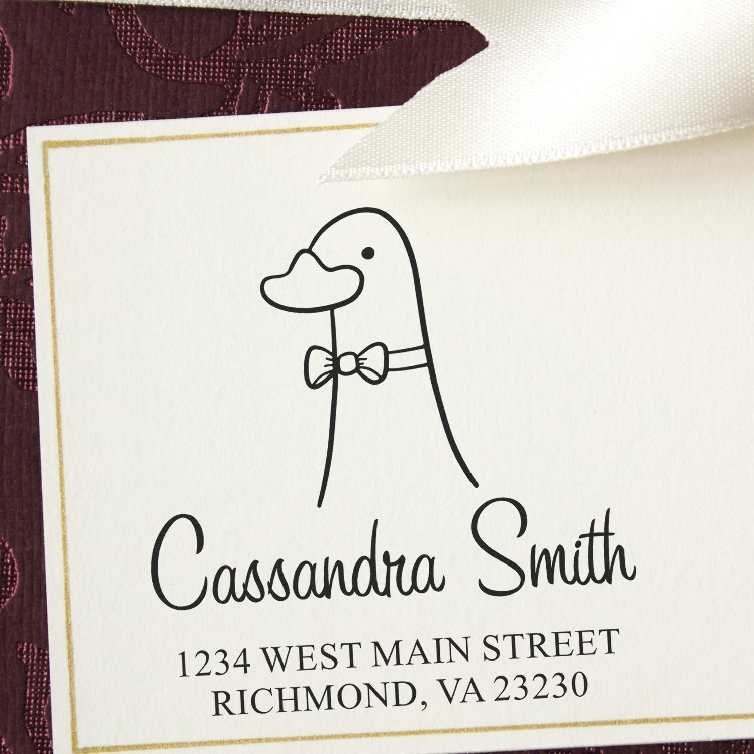 Wood Handle Dashing Duck Cartoon Animal Custom Name And Address Stamper on an envelope. The stamp features a duck with a bow tie, customizable for return mail. Text reads "Cassandra Smith, 1234 West Main Street, Richmond, VA 23230."
