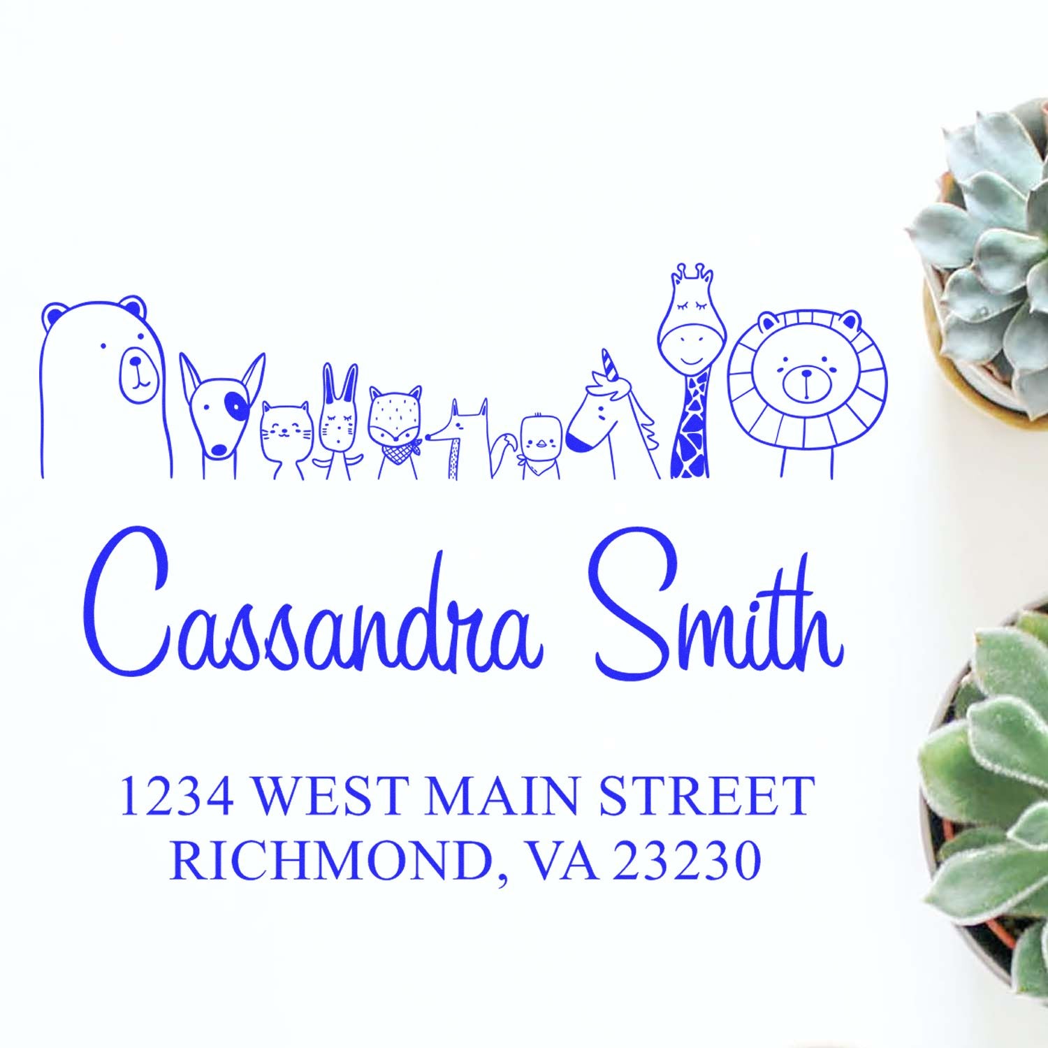 Portable Pre-Inked Zany Zoo Made To Order Home Address Stamper featuring whimsical animal illustrations and the name "Cassandra Smith" with the address "1234 West Main Street, Richmond, VA 23230." Custom-Made Mailing Stamp next to potted succulents.