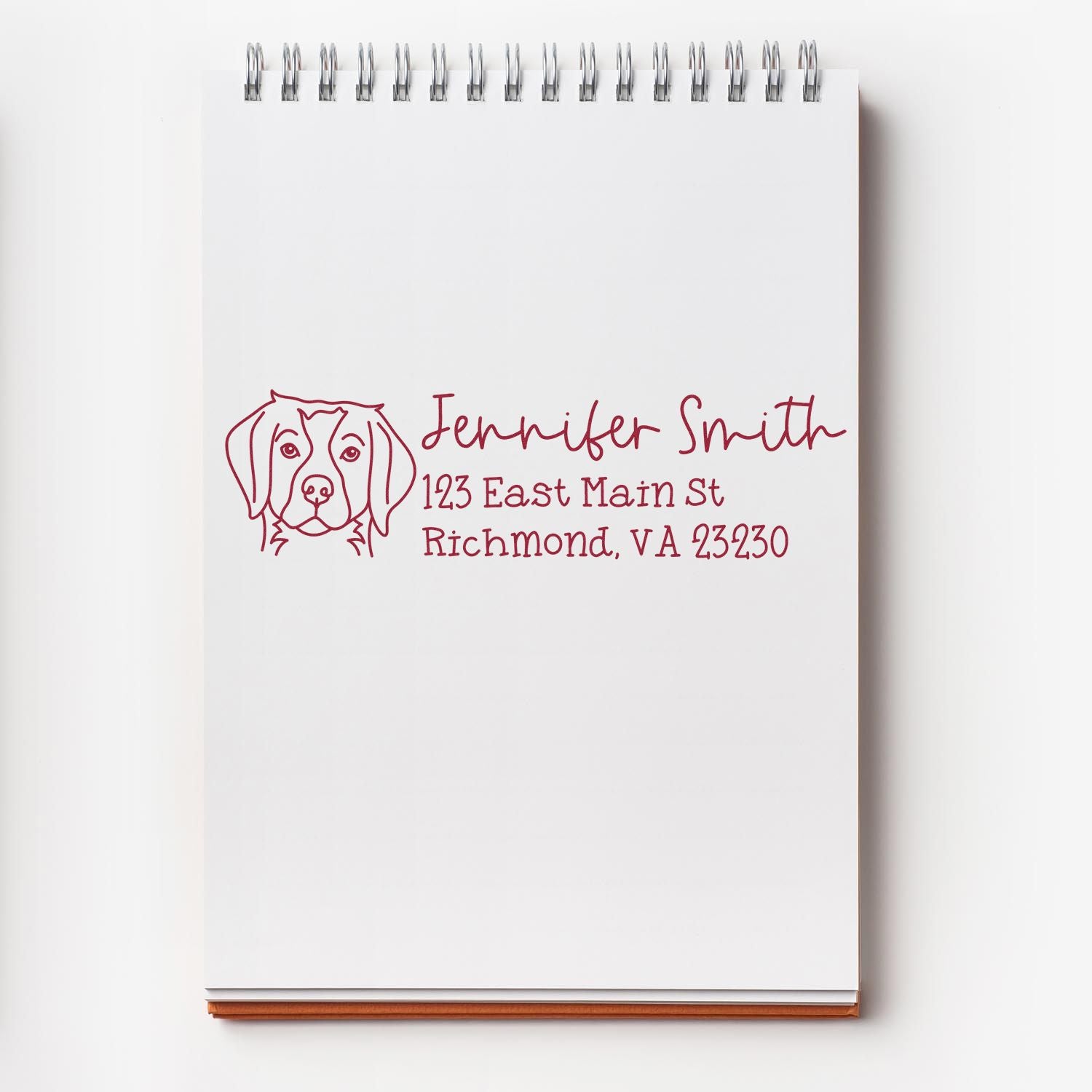 Burgundy custom address stamp and seal with dog illustration on a white spiral notebook, Jennifer Smith, Richmond VA