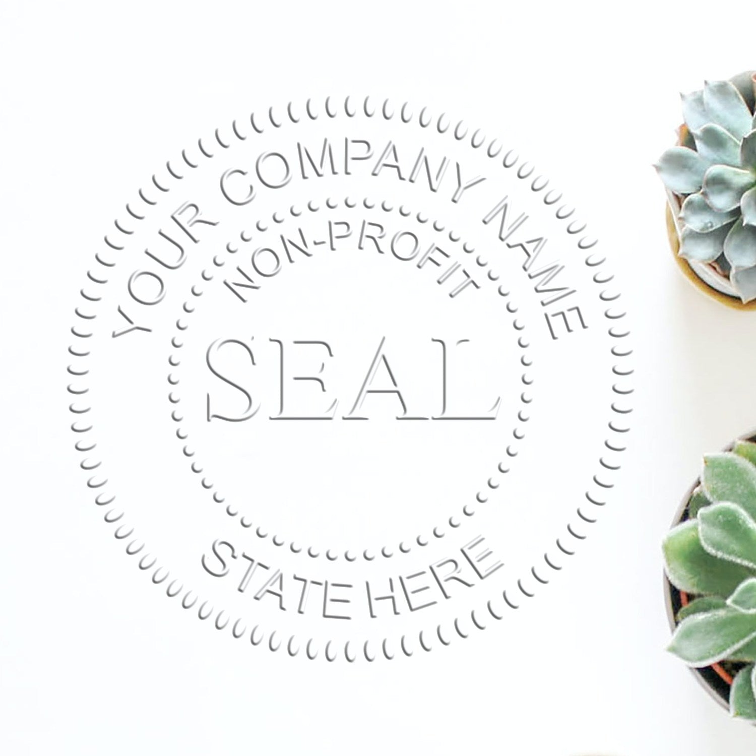 Gray circular stamp and seal with Your Company Name, Non-Profit, and State Here on white, beside succulents.