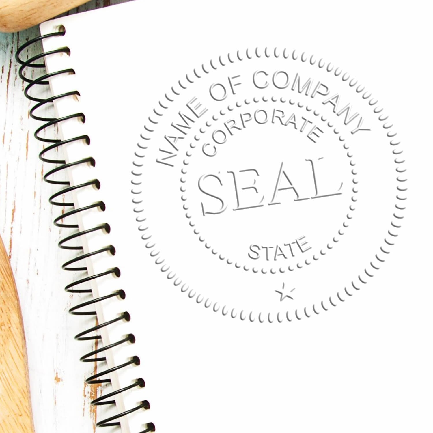 Round gray corporate seal stamp with dotted border and NAME OF COMPANY text on a white spiral notebook.