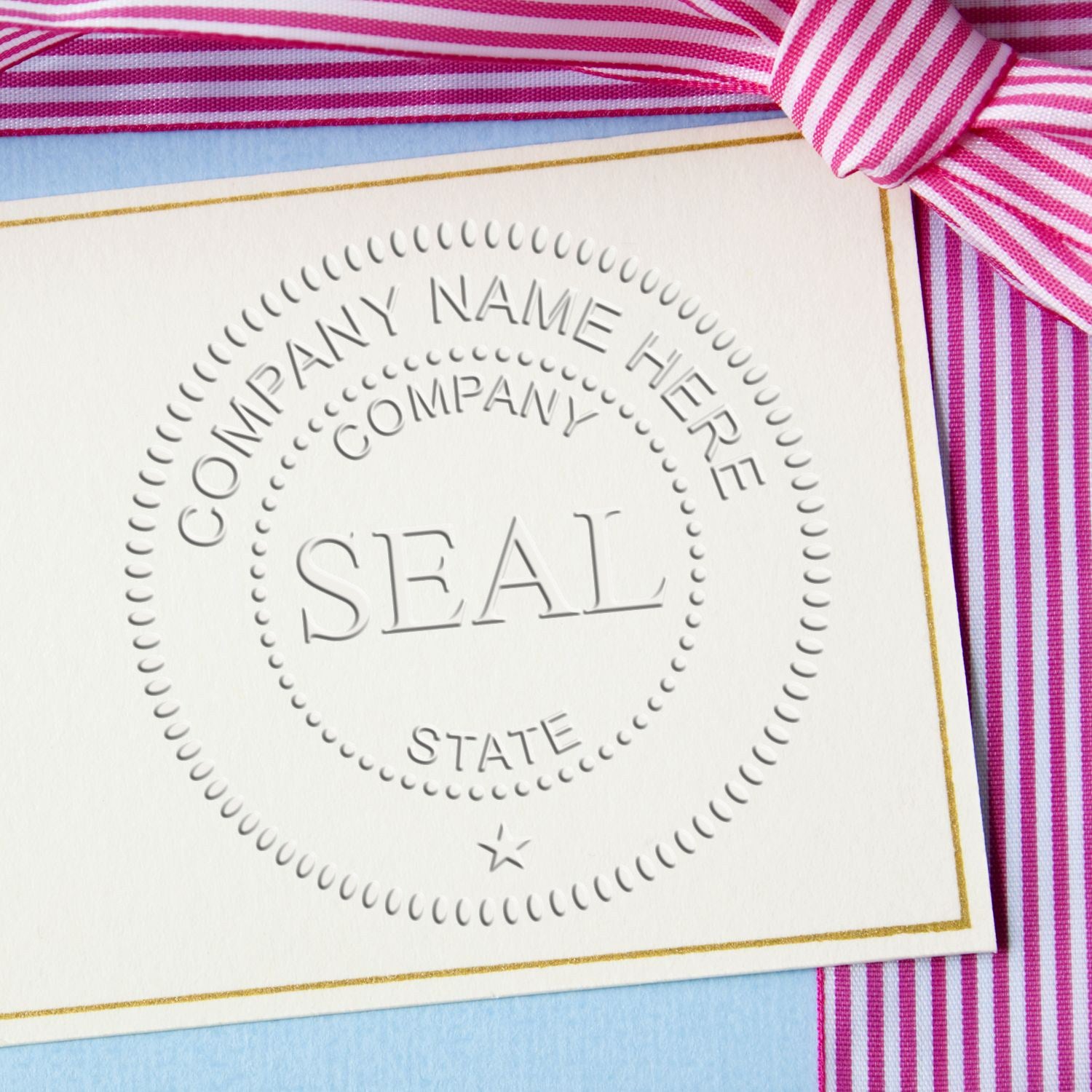 White embossed company seal stamp with gold border and pink striped ribbon on stationery