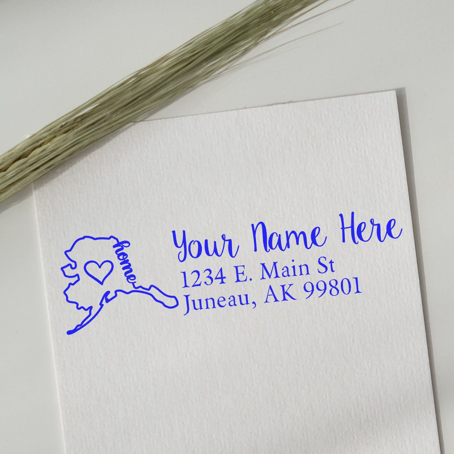 Alaska state map rubber address stamp with wooden handle by ESS, in use for custom return address stamping.