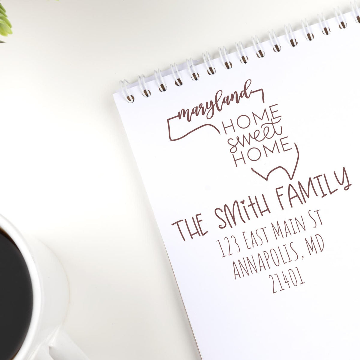 White spiral notebook showing a brown custom address stamp seal for The Smith Family, Maryland home sweet home.