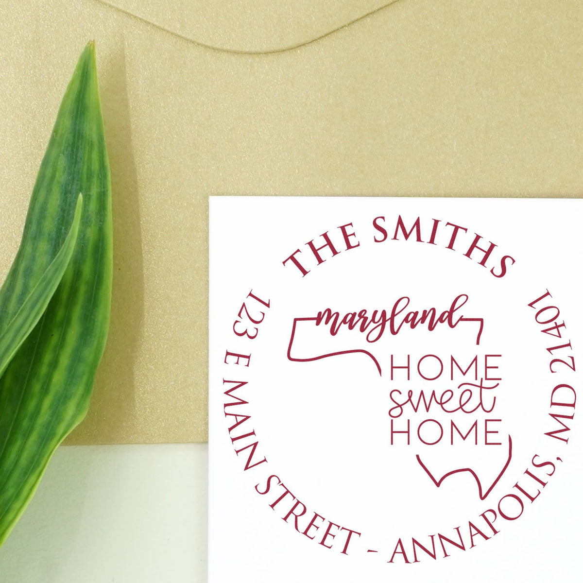 White custom stamp and seal card with maroon Maryland Home Sweet Home address design beside a green leaf.