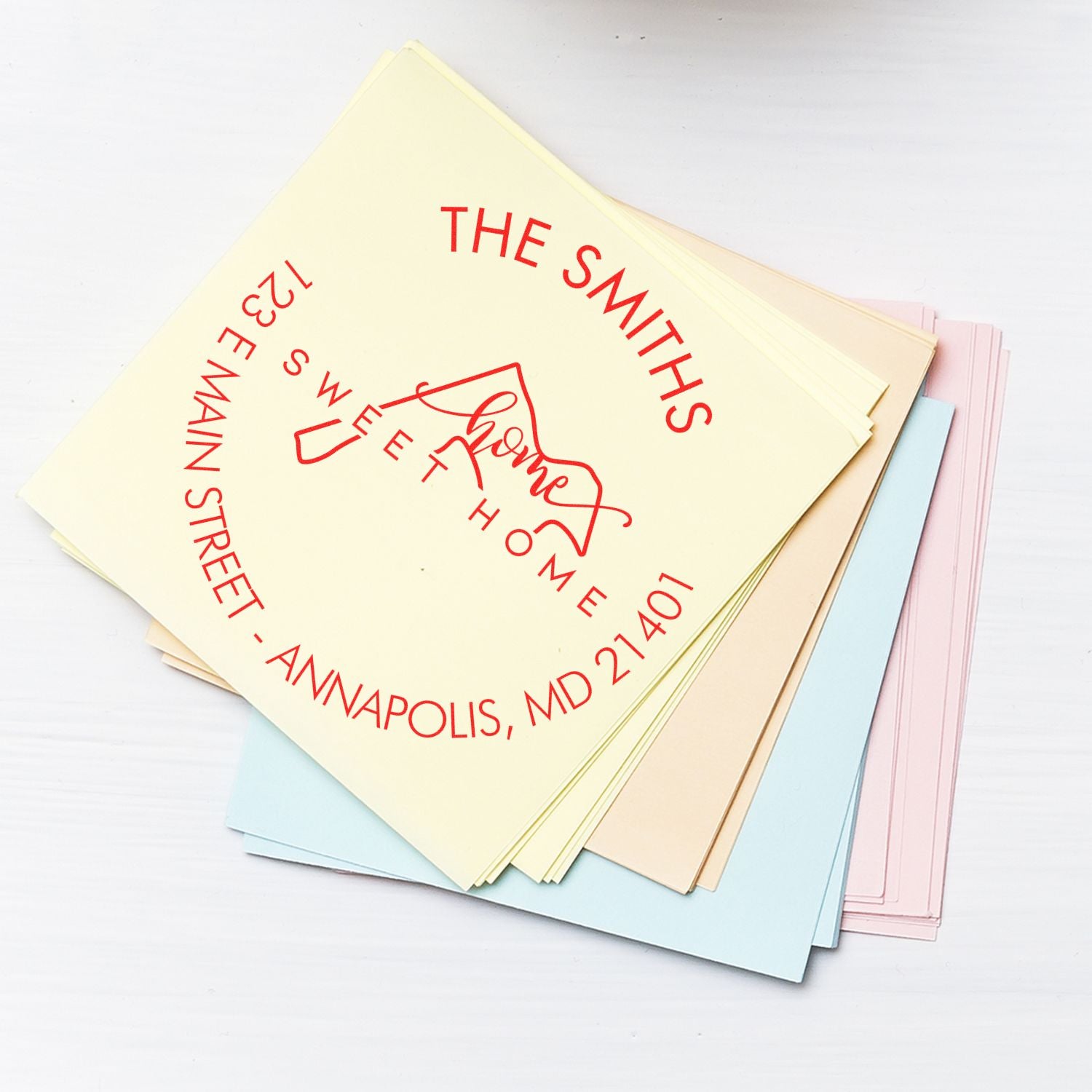 Pastel paper stack featuring red custom address stamp and home seal logo for The Smiths, Annapolis, MD.
