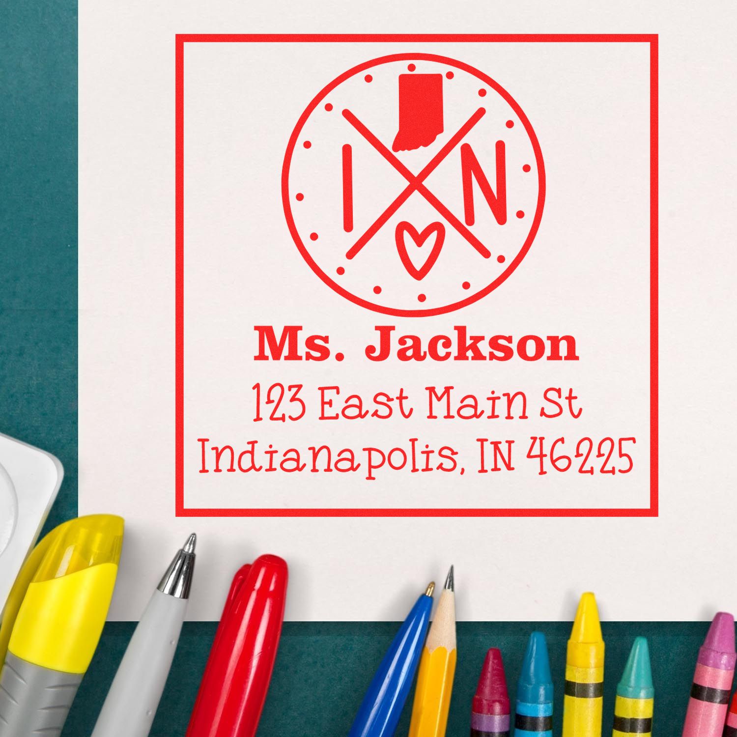 Red custom address stamp and seal for Ms. Jackson, with Indiana heart logo, on white paper beside colorful pens