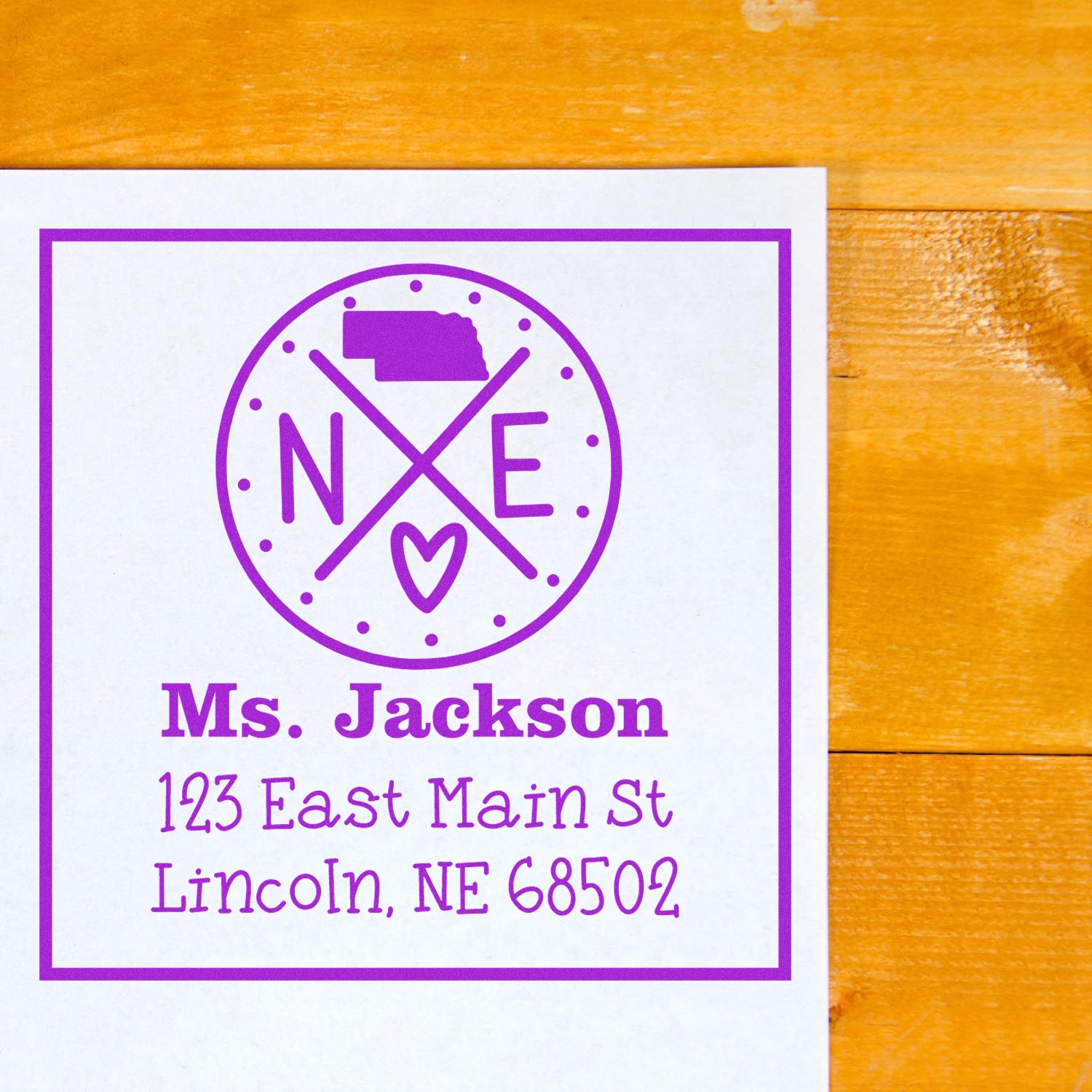 Purple custom stamp and seal for Ms. Jackson with name and address on white paper over a warm wood background.