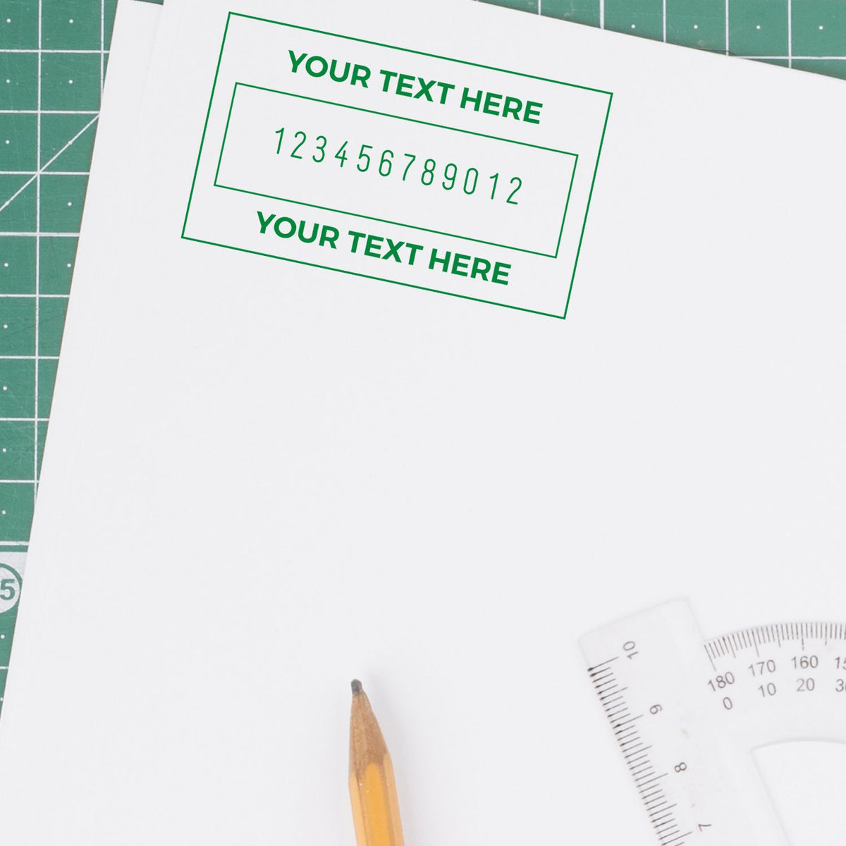Custom green stamp and seal design on white paper, with placeholder text and numbers over a cutting mat, pencil, and ruler.