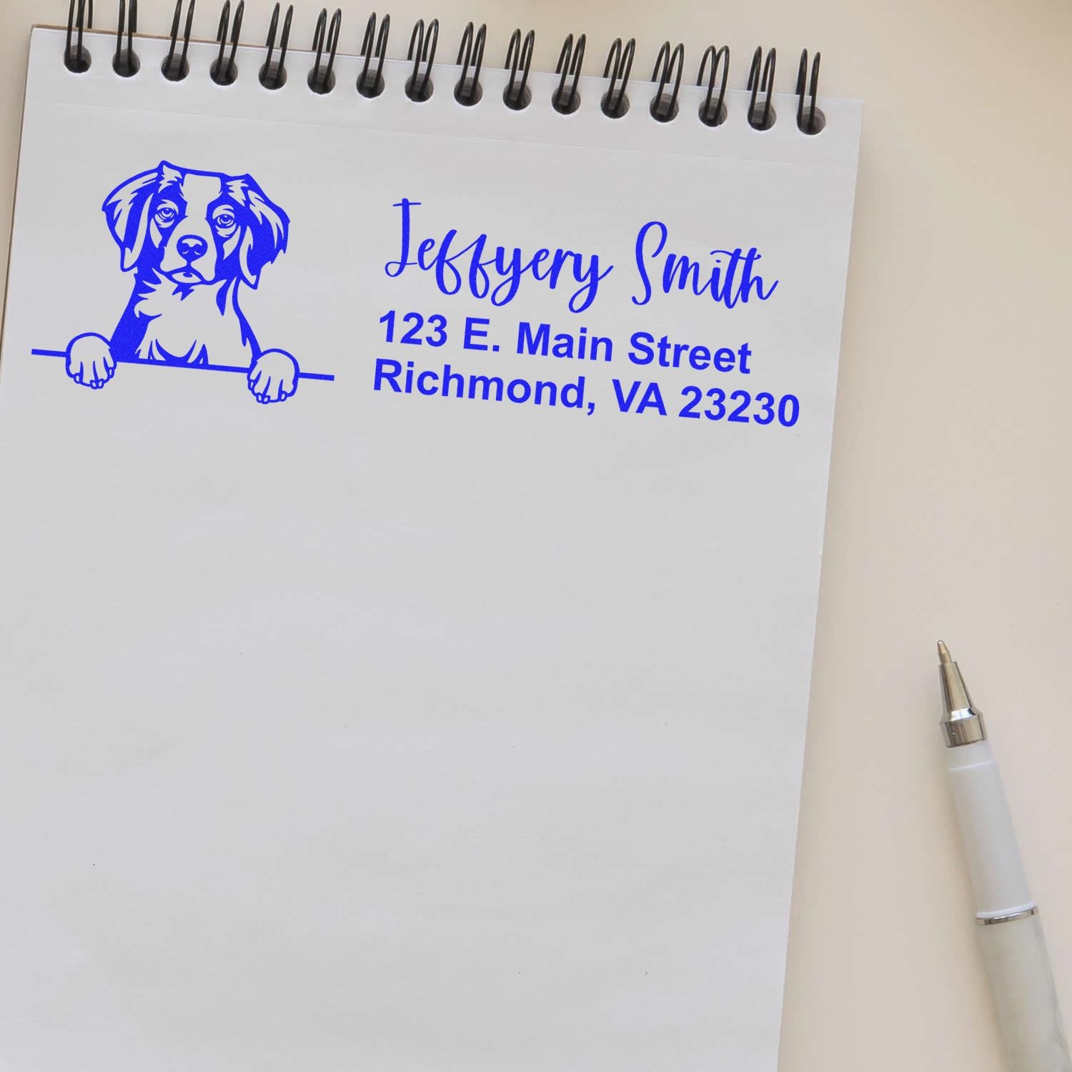 Blue custom stamp seal with dog logo, Jeffery Smith name, and Richmond, VA address on a white spiral notepad.