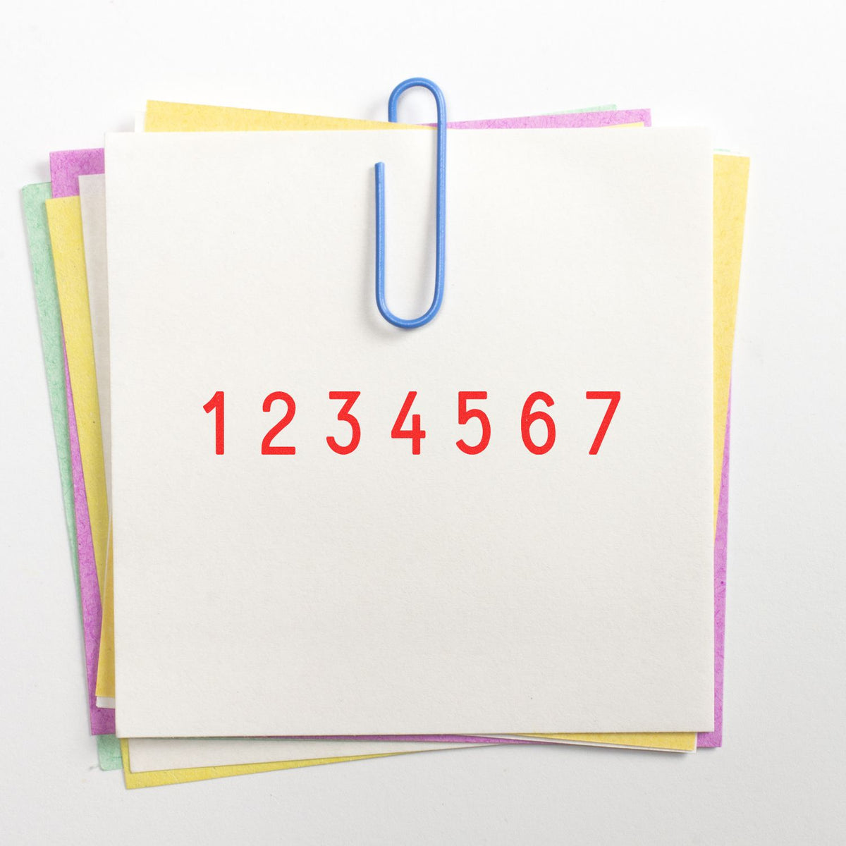 Numbered stamp and seal product sheets clipped with a blue paperclip, layered on pastel yellow, pink and green paper.