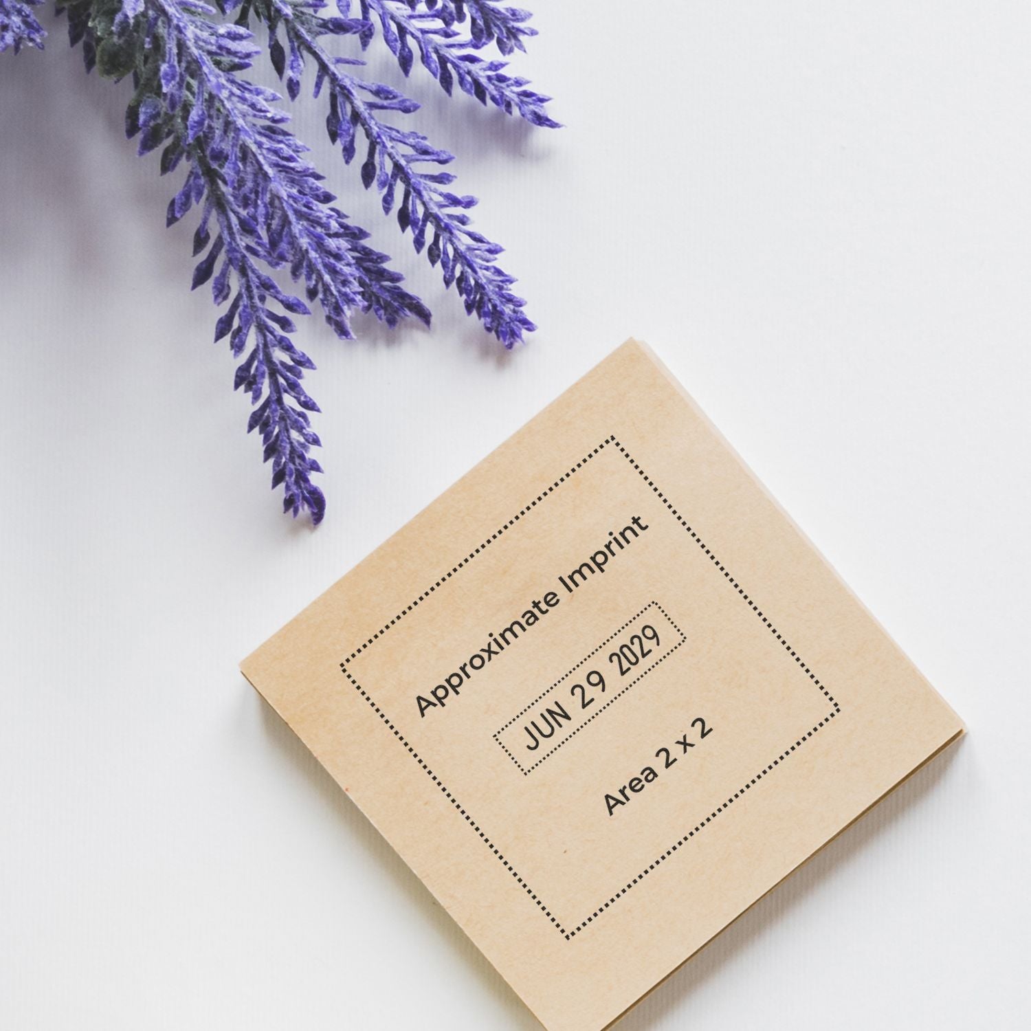 Beige stamp seal sample with black dotted border and text, beside purple lavender sprigs on a white background.