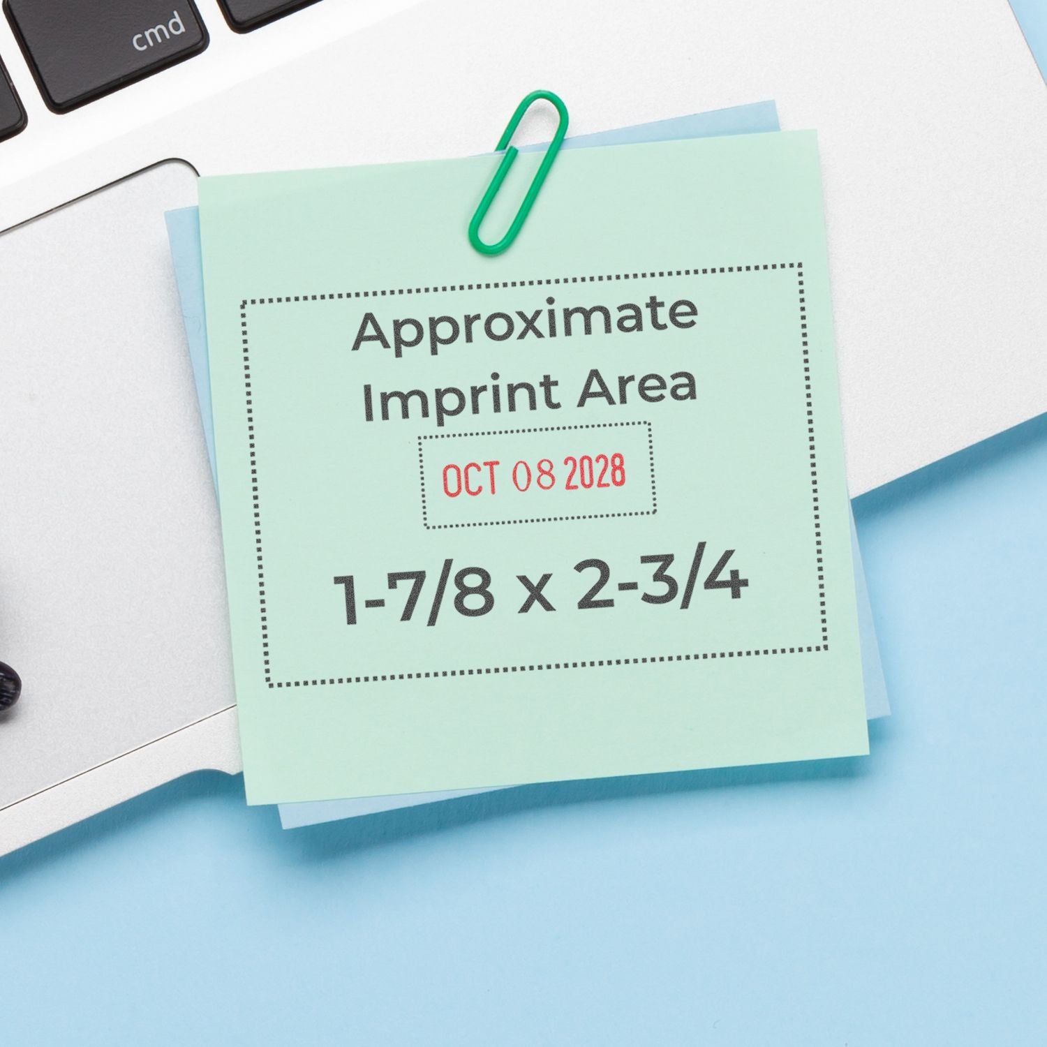 Mint green custom stamp and seal sample with dotted imprint box, red date text, and green paperclip on blue-white desk.