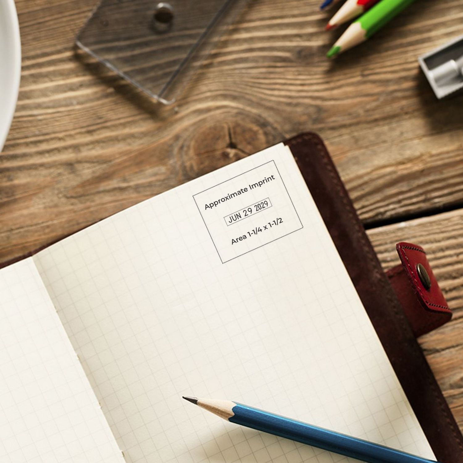 Stamp and seal product showing black approximate imprint on cream notebook page, with blue pencil on a brown wood desk.